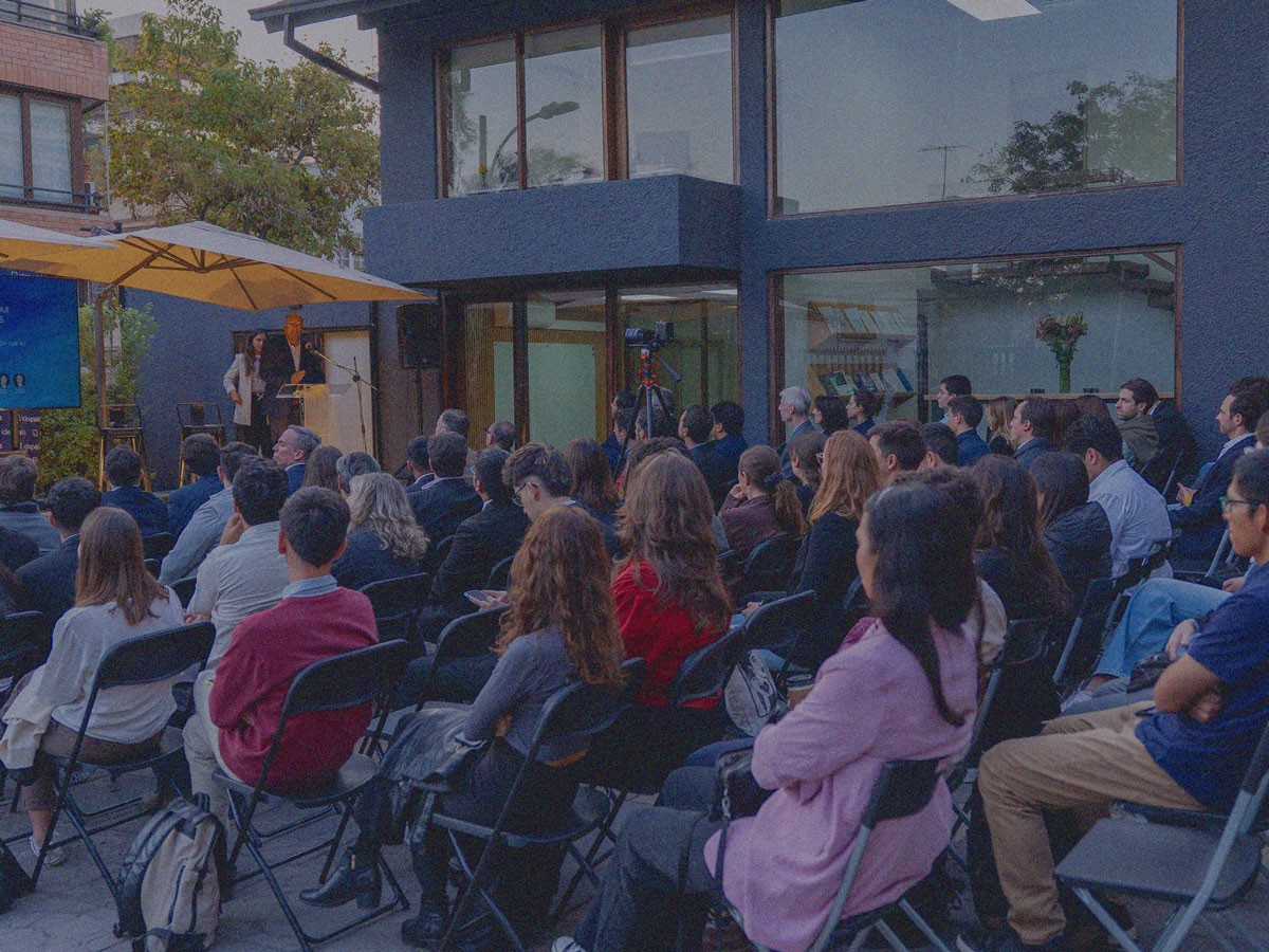 Personas sentadas en evento realizado en el frontis de la oficina De Santiago de IdeaPaís.