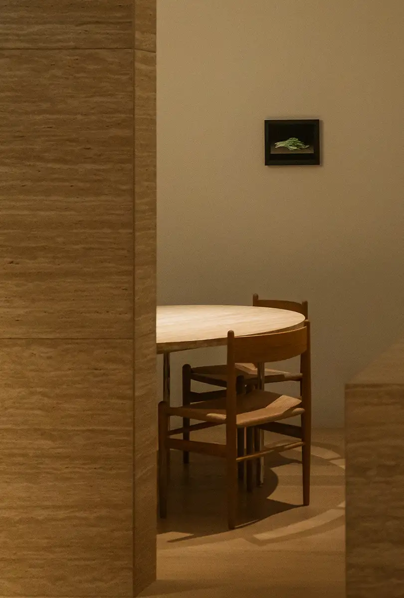 부드러운 조명 아래 원형 테이블과 나무 의자가 배치된 미니멀한 실내 인테리어