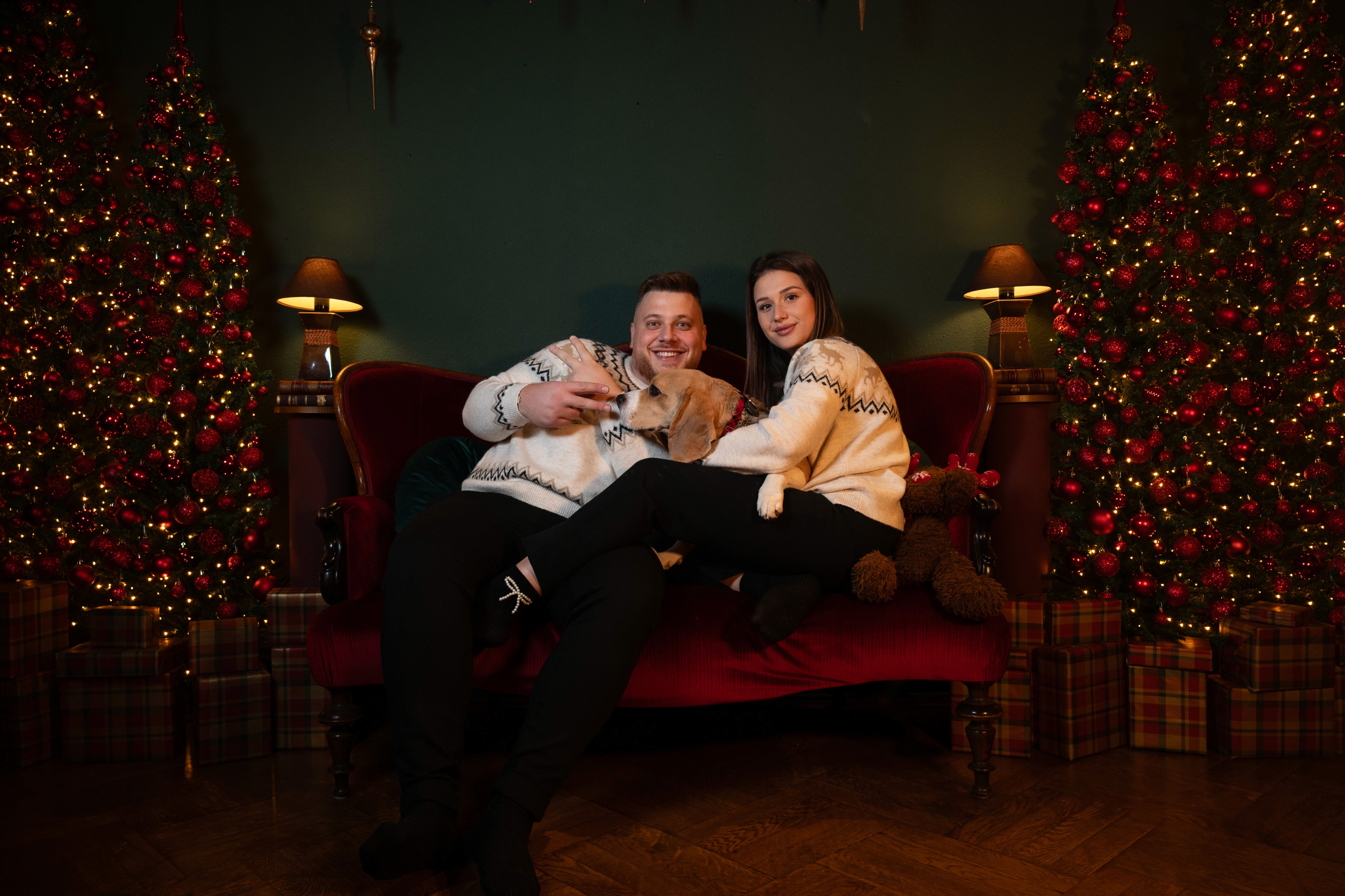 Ședință foto de cuplu de Crăciun pe canapea, atmosferă cozy în studio