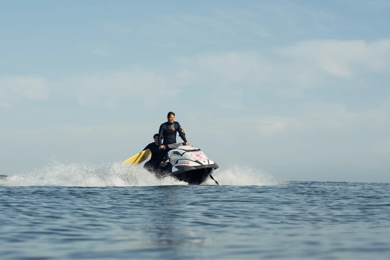 Jet Ski operator guiding a surfer in the ocean.
