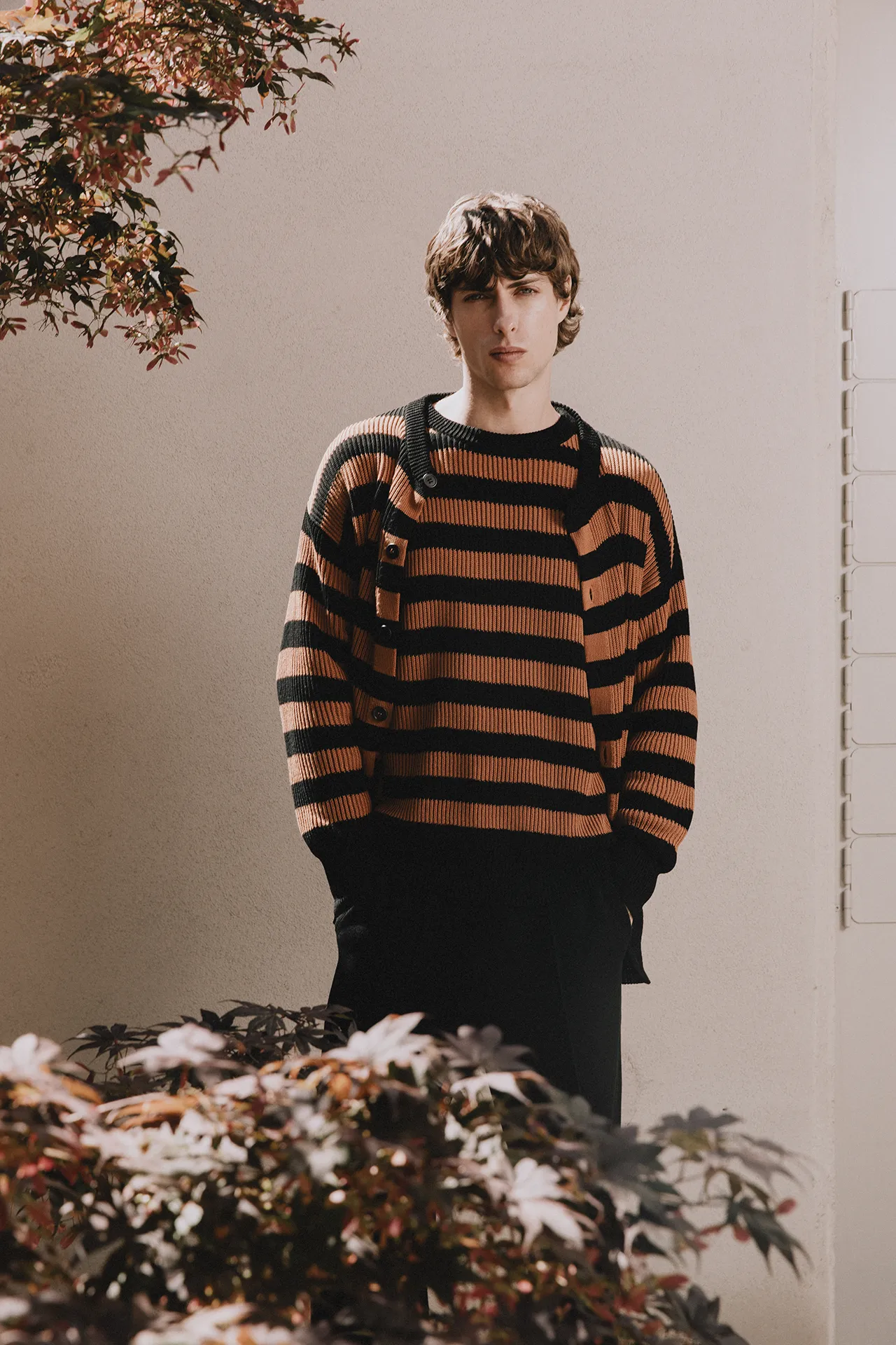 Annapurna SS26 collection men's ribbed knit cardigan featuring bold black and camel stripes with an asymmetrical button placket.