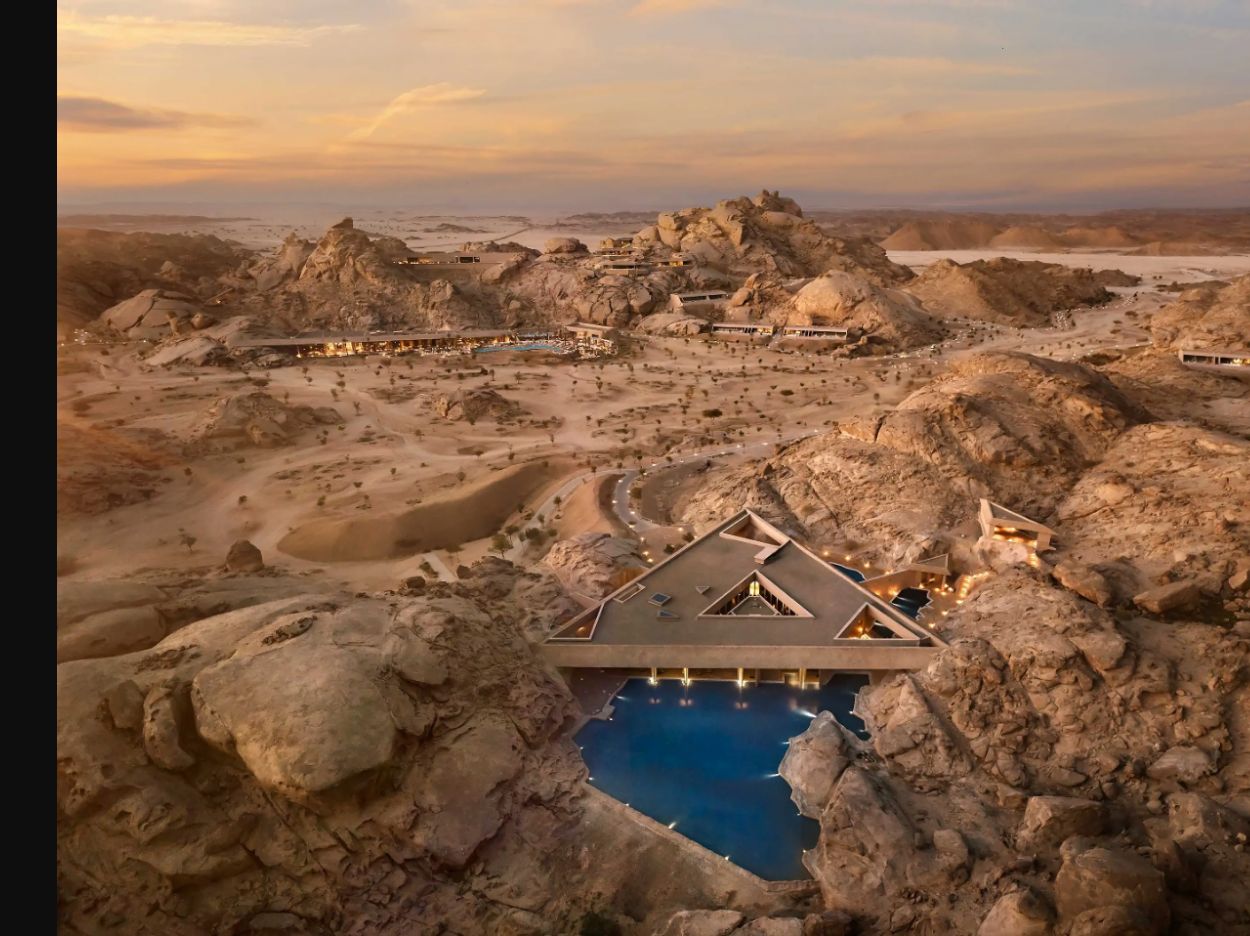 Remote Saudi desert luxury resort integrated into rocky landscape at sunset, with secluded pool and warm architectural lighting