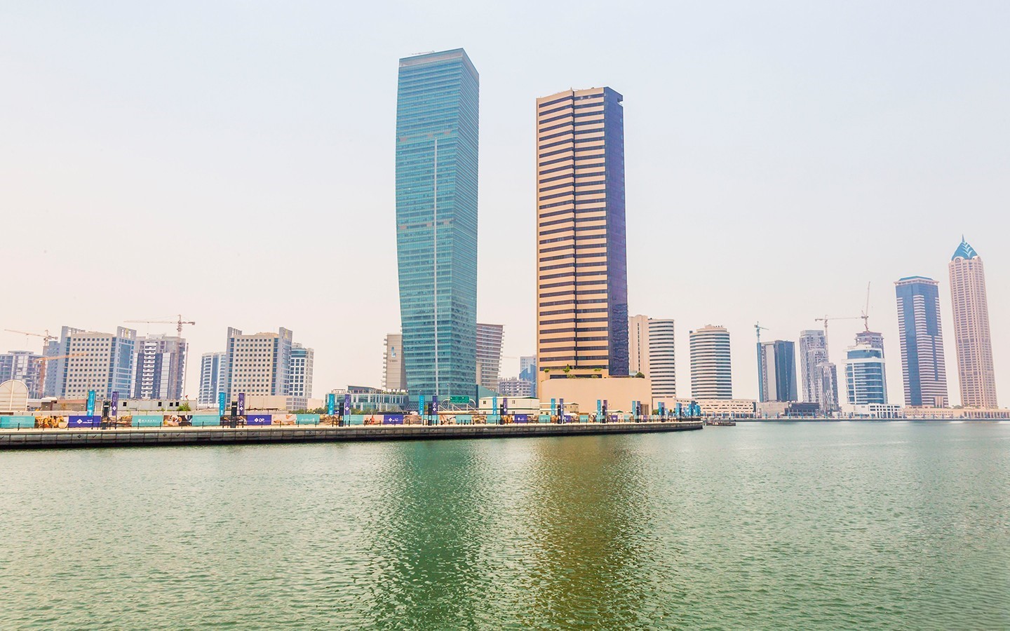Skyscrapers along the waterfront in Business Bay with modern towers reflecting over calm water.
