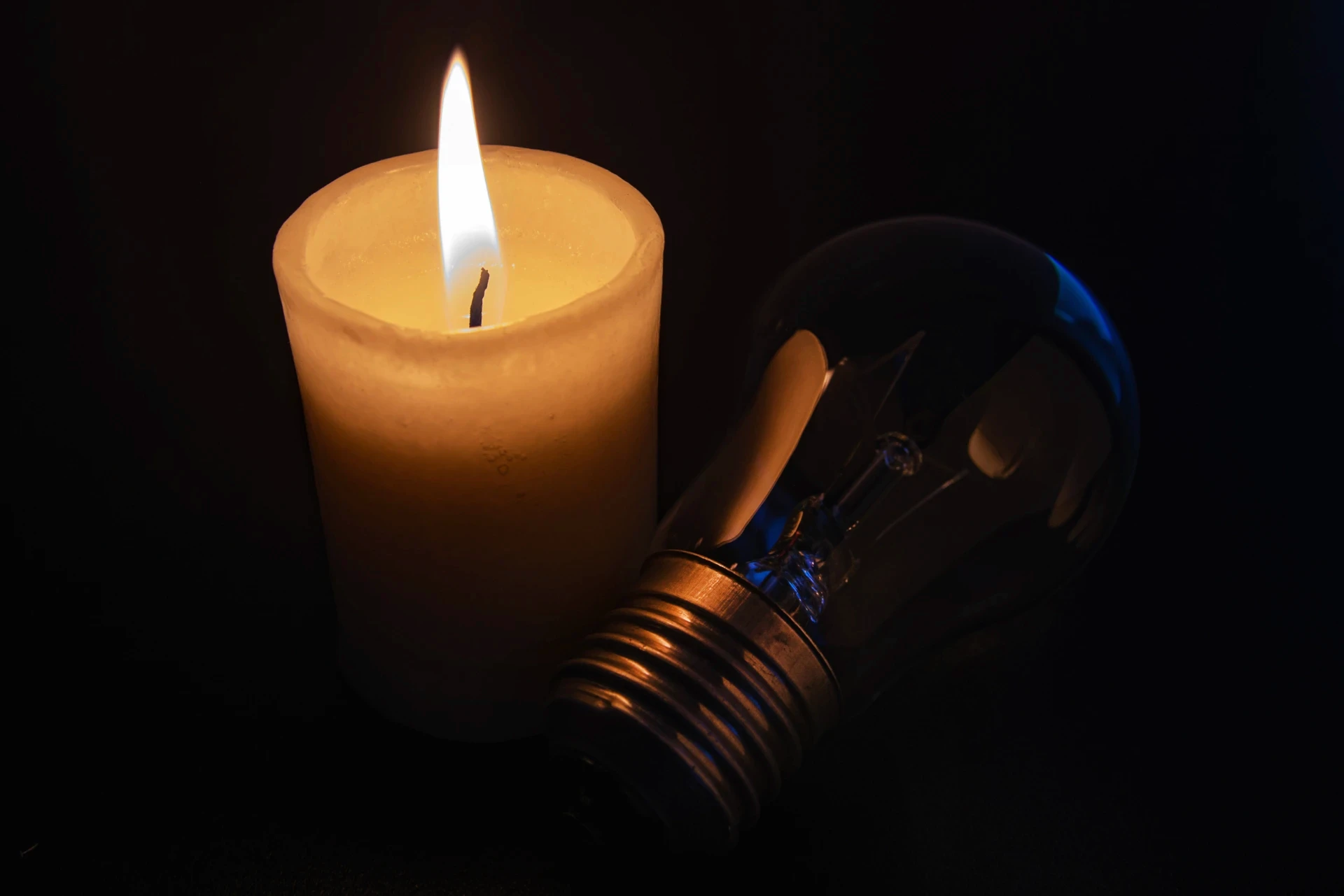 eine flammende Kerze neben einer Glühbirne