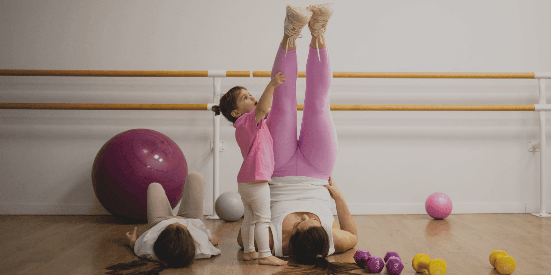 Jeune maman souriante faisant des exercices au sol sur un tapis de sport à côté de son bébé.