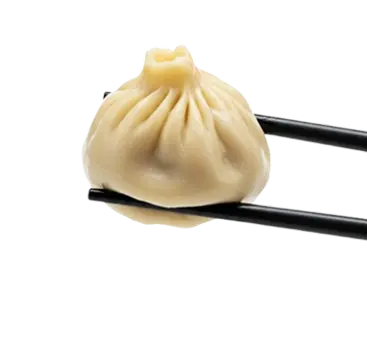 A steamed soup dumpling held with black chopsticks.