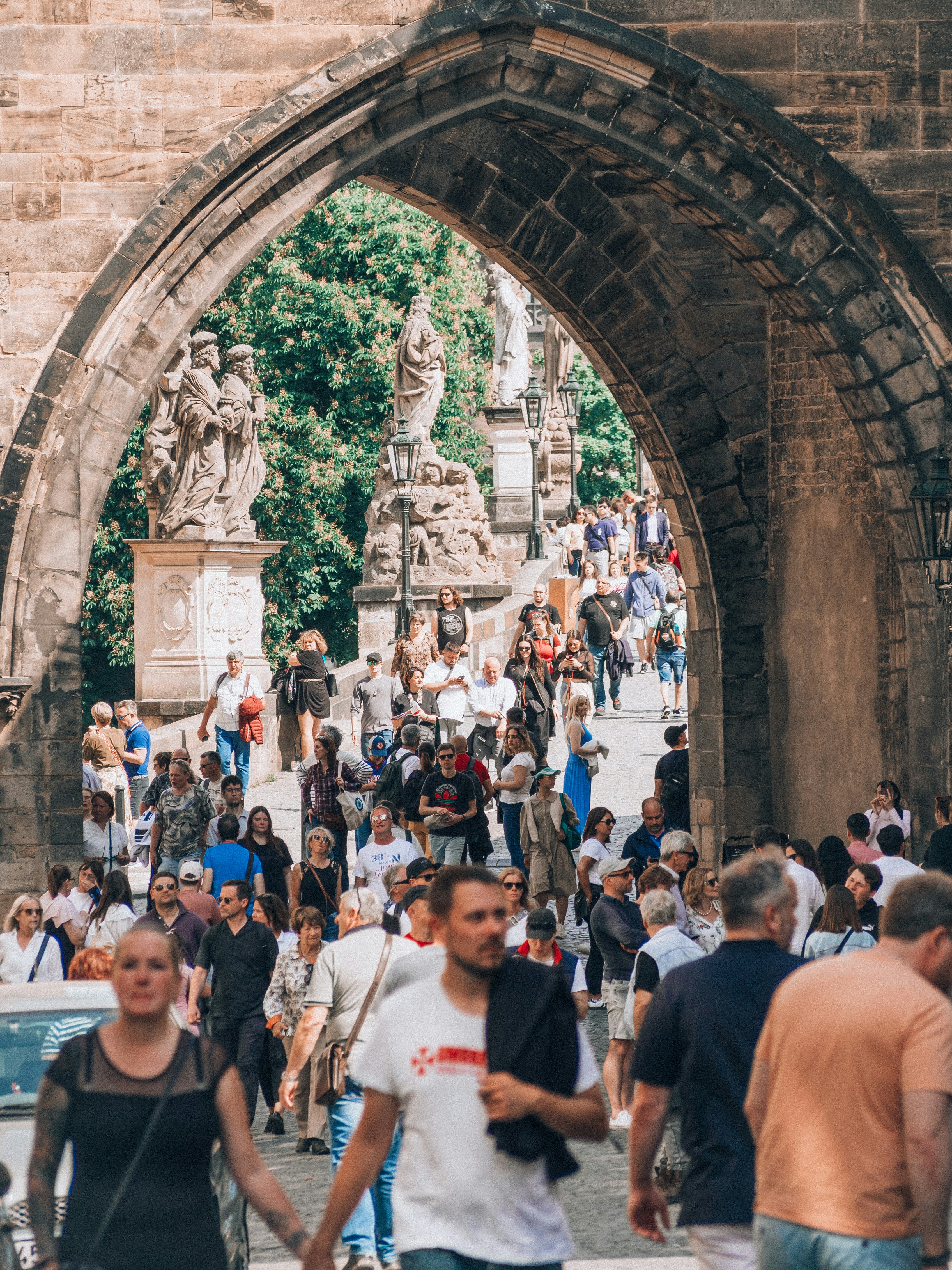 a crowd of people walking under a stone arch