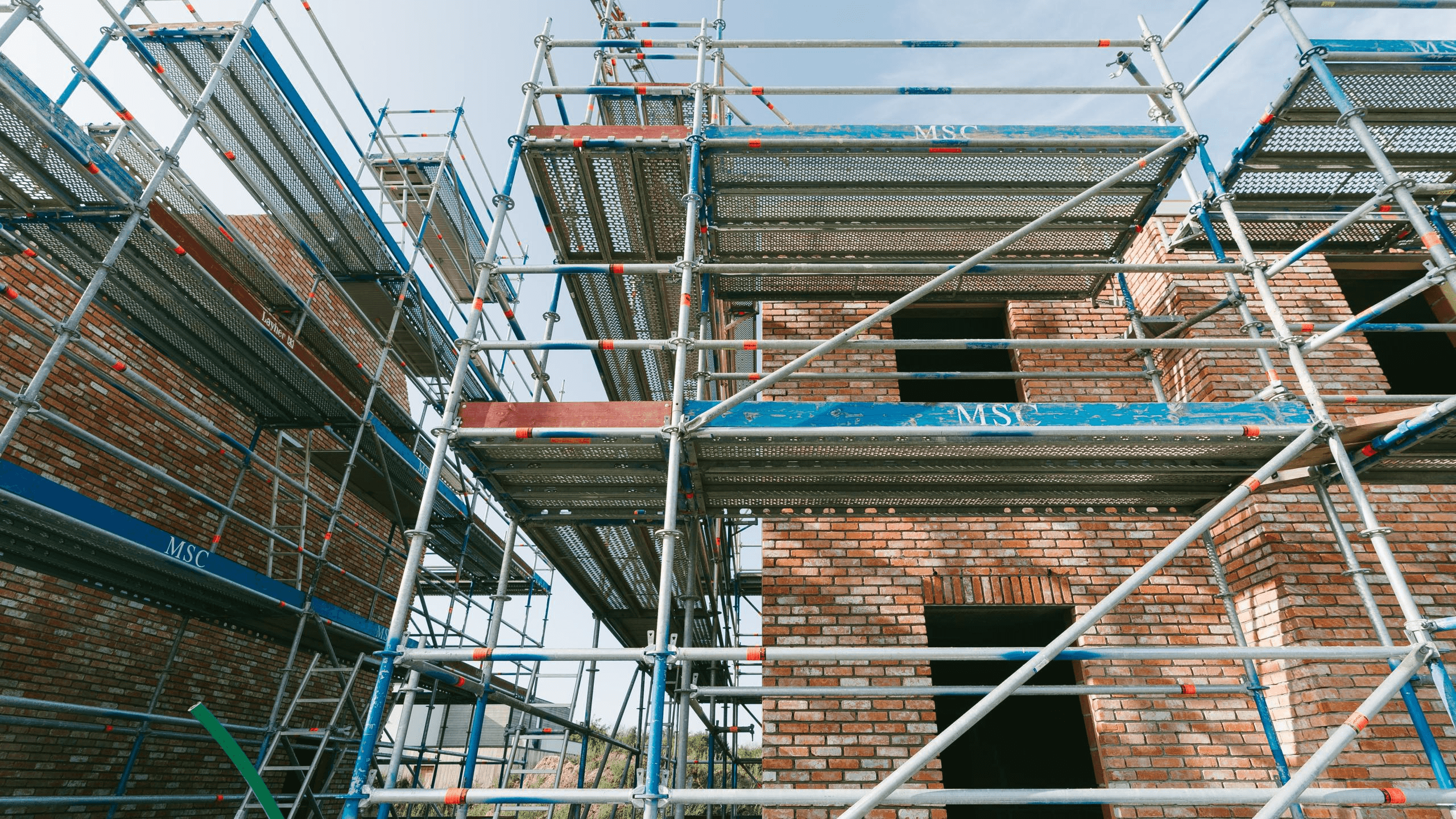 man in orange and black vest wearing white helmet holding yellow and black power tool