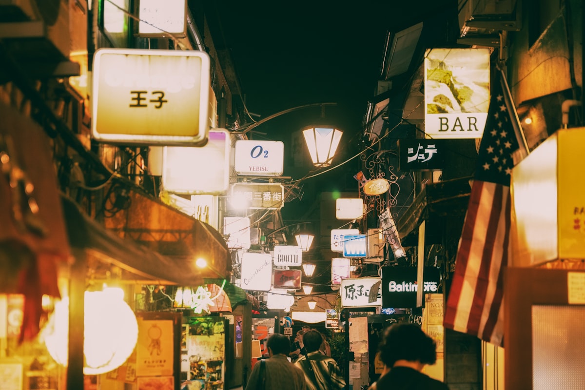 Narrow alley in Golden Gai, Shinjuku filled with glowing neon signs and tiny bar entrances at night