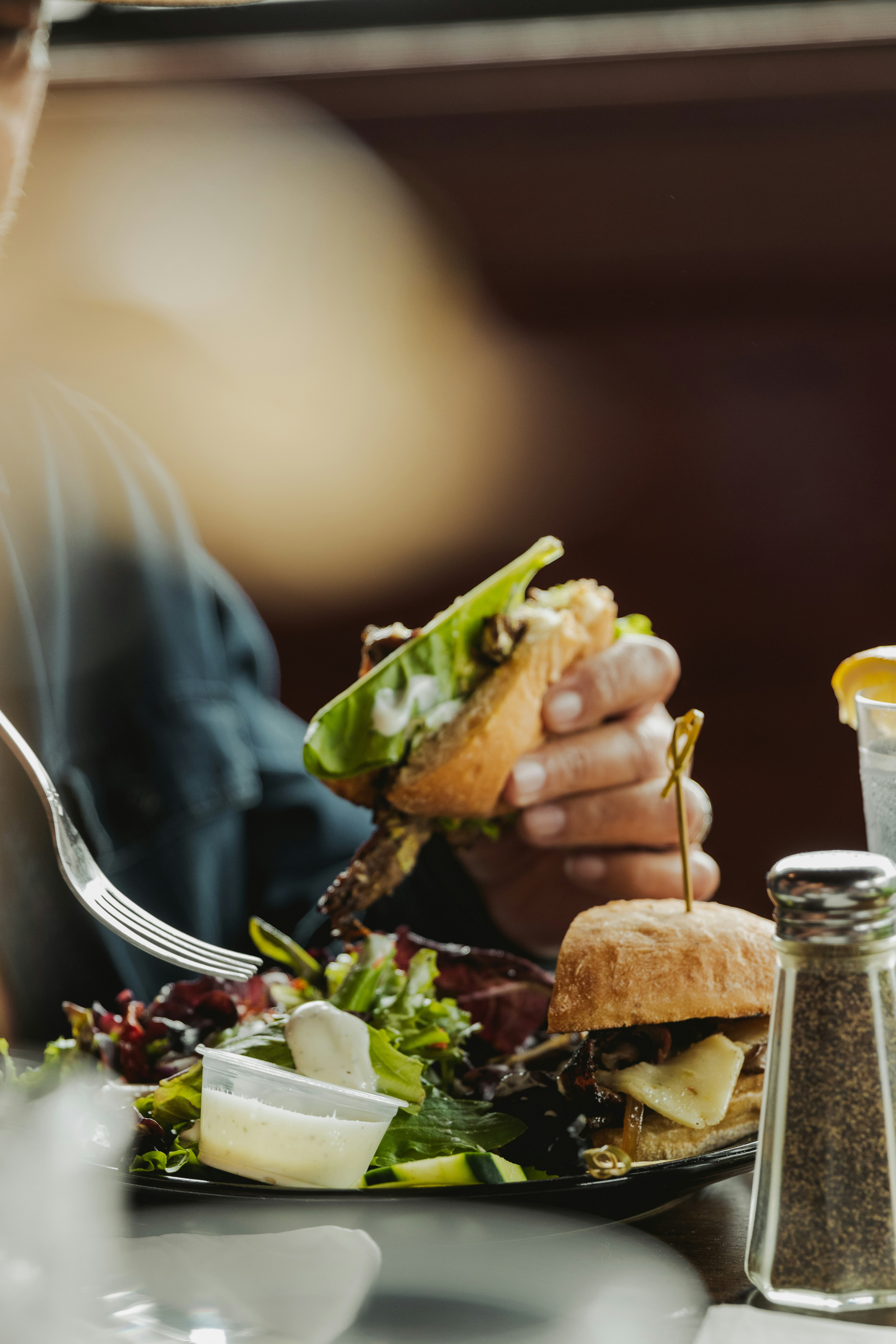 A smiling young man with crossed arms, wearing a plaid shirt and white t-shirt, poses against a dark background.