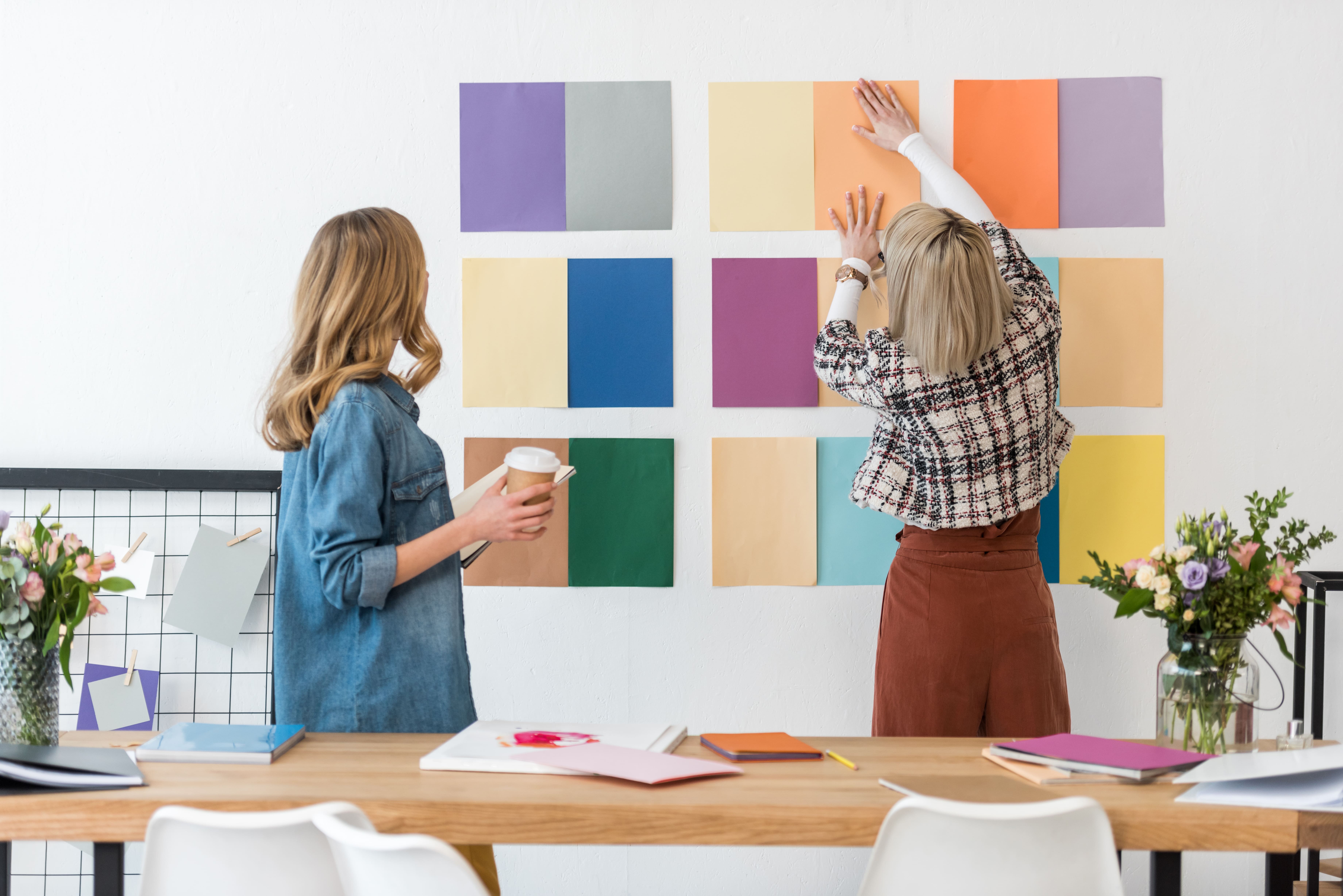 Two individuals carefully reviewing and selecting color options on a wall, ensuring alignment with brand guidelines for a cohesive and visually appealing aesthetic.