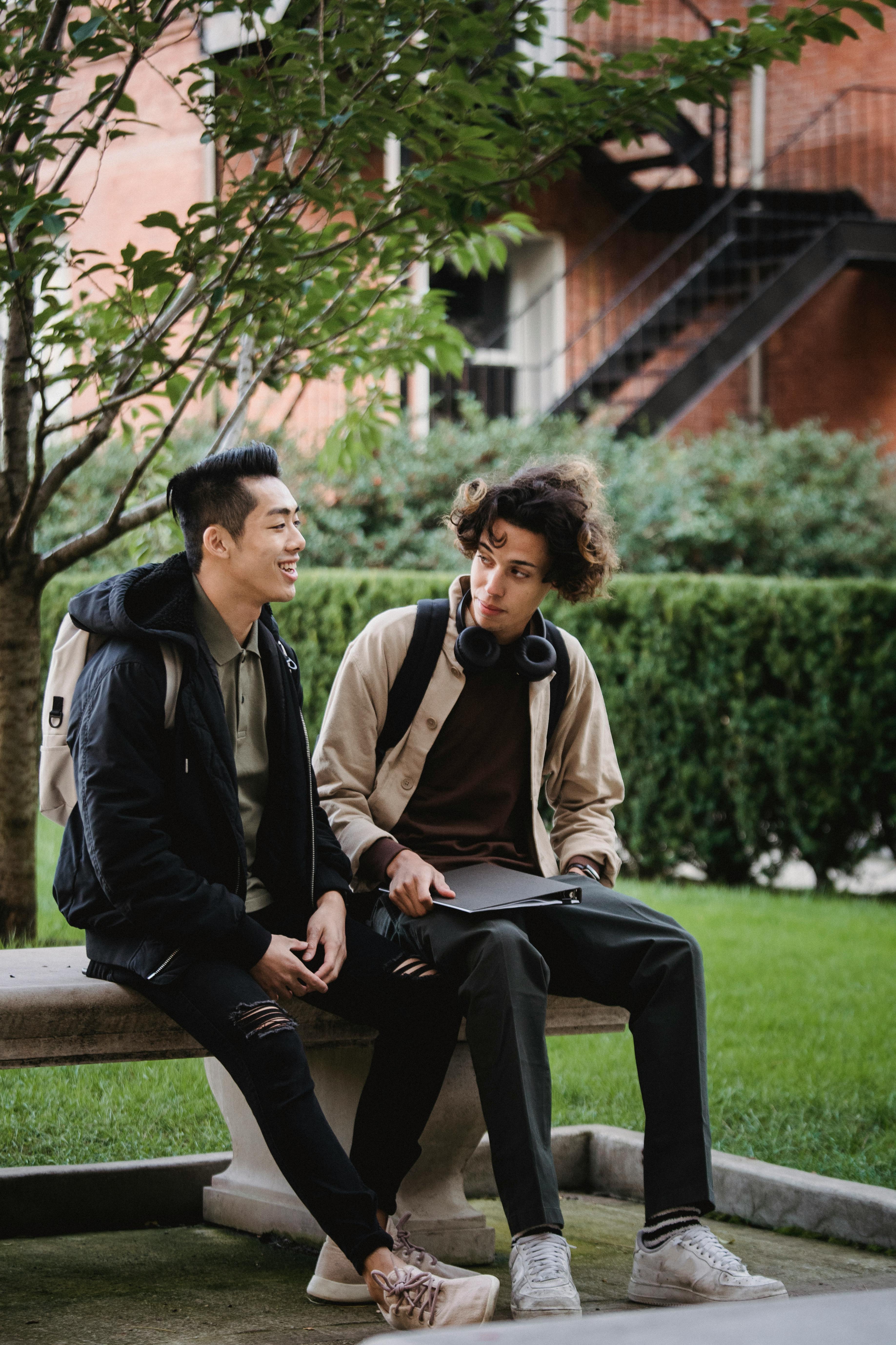 Two friends talking on a park bench