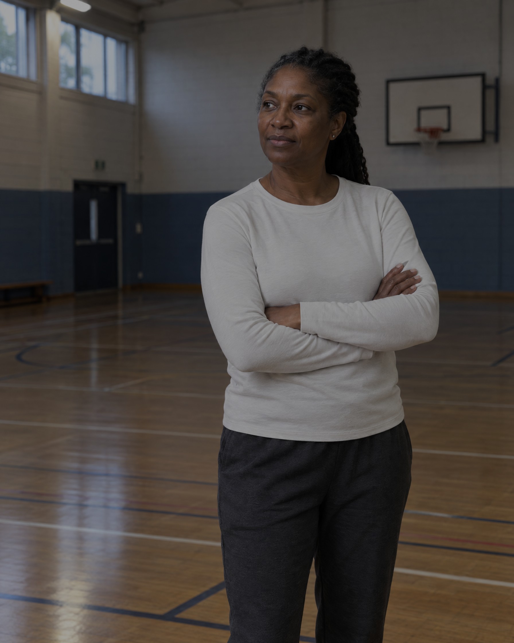 Grace Adeyemi, head of basketball, standing on the sports hall floor with arms folded