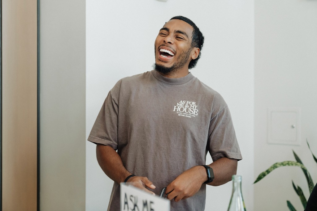 A speaker on stage, illuminated against a dark background, gestures while addressing an audience.