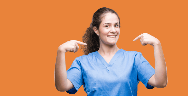 Smiling healthcare worker in scrubs pointing at herself on an orange background