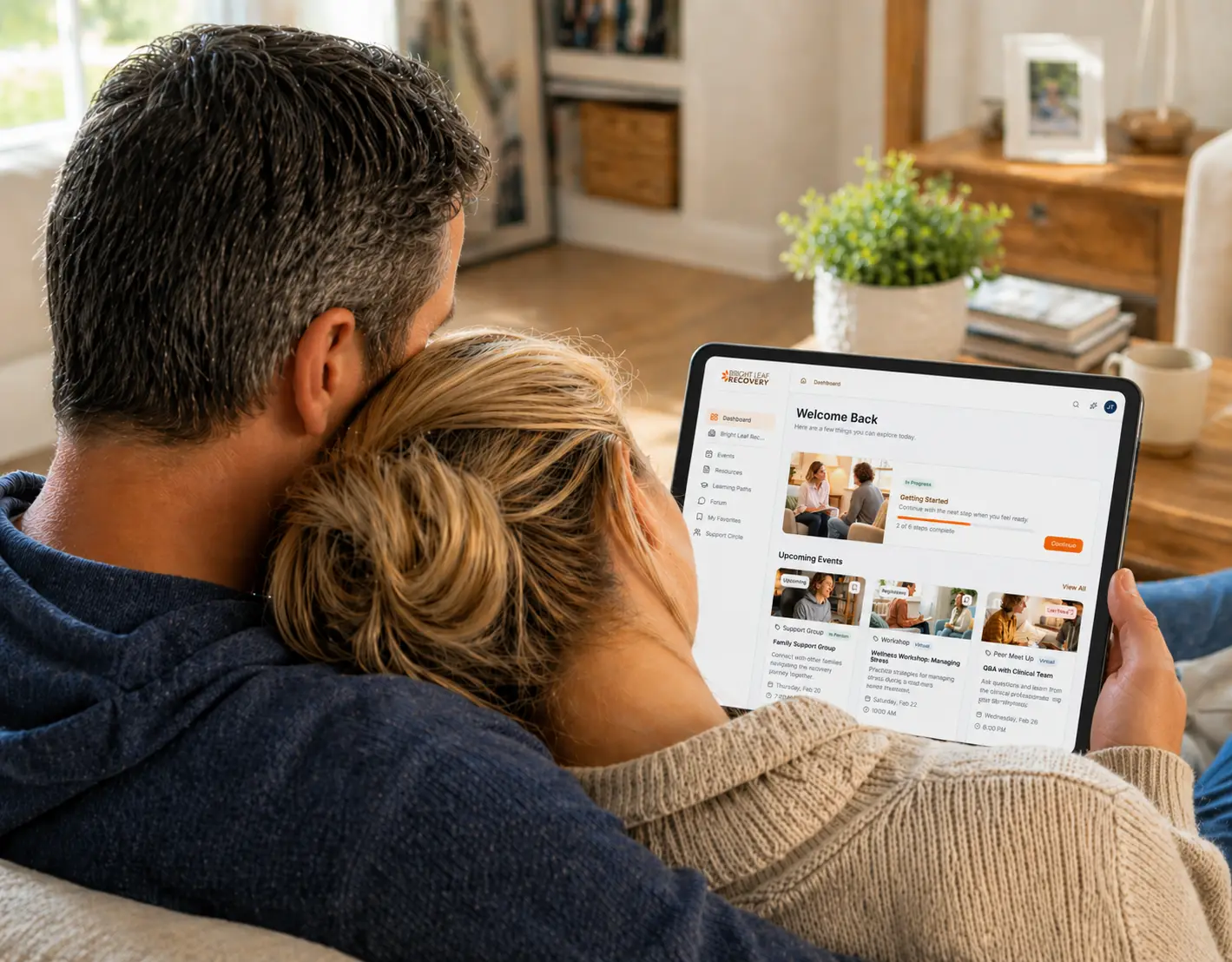 Couple looking at a tablet together in their home, embracing.