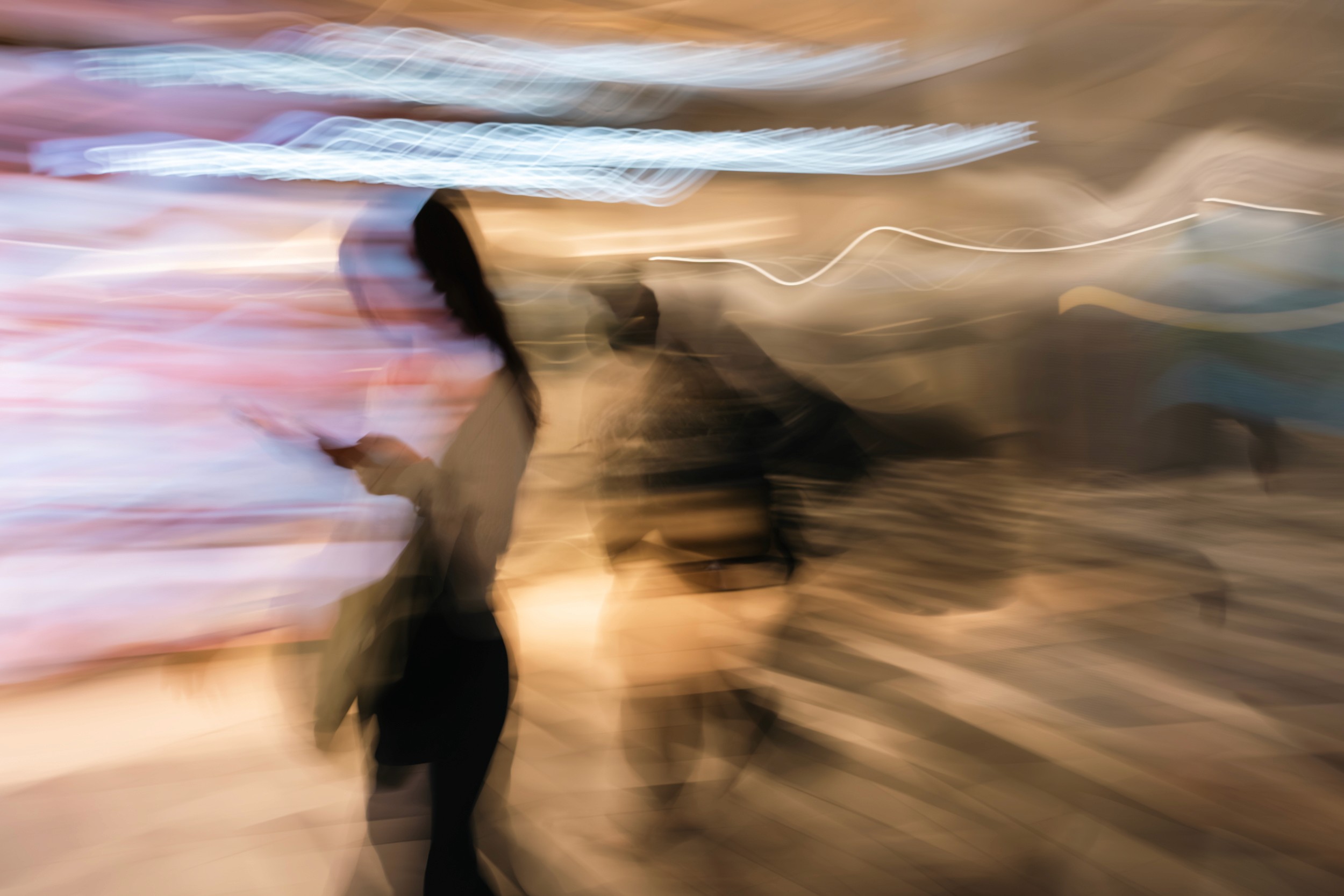 Black and white abstract motion blur of people walking inside a brightly lit metro station.