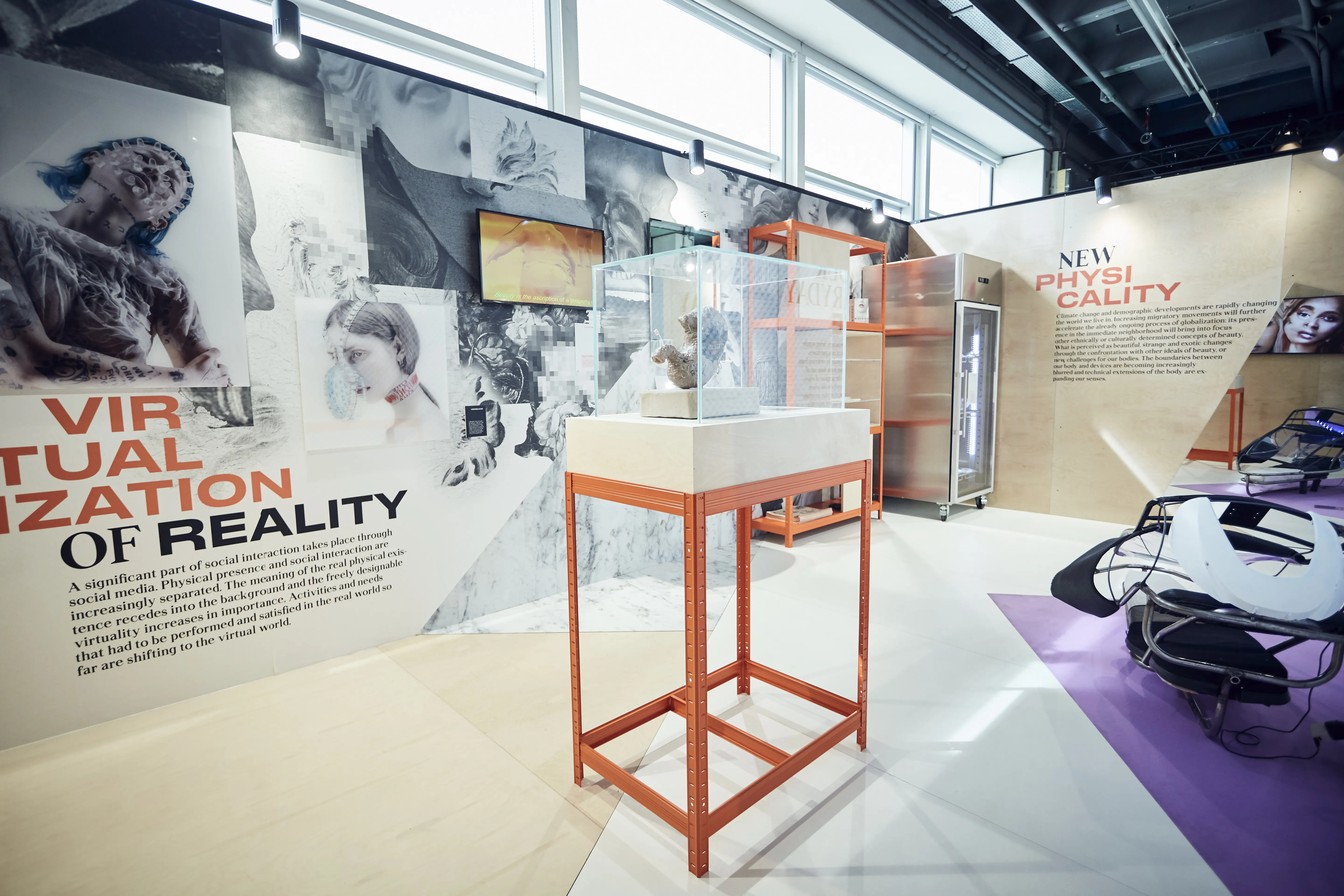 Exhibition stand of the Cosnova Future of Body and Beauty show with a glass display case on an orange rack and collage walls on virtual reality.