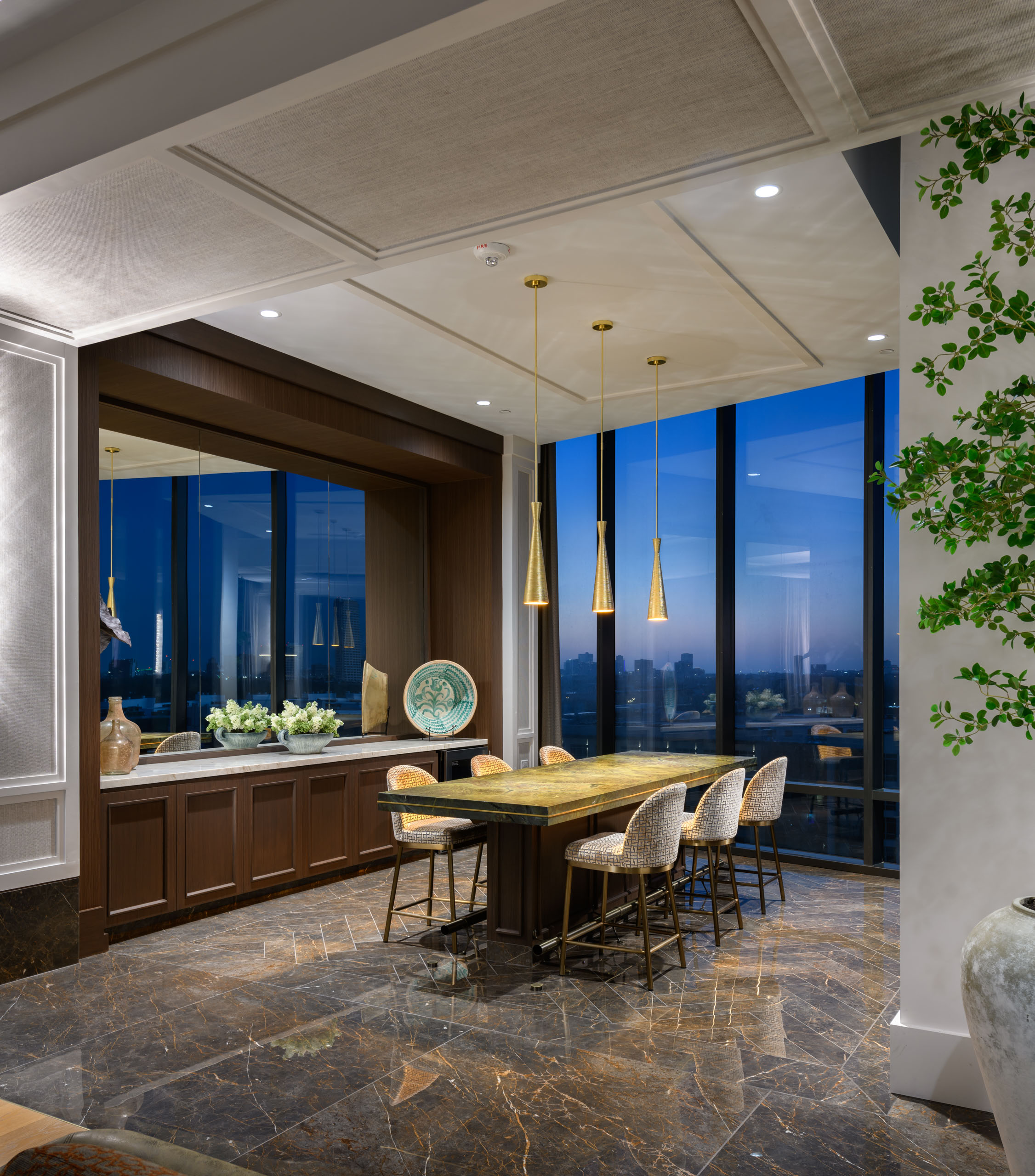 Dining area with bar seating and city view at dusk.