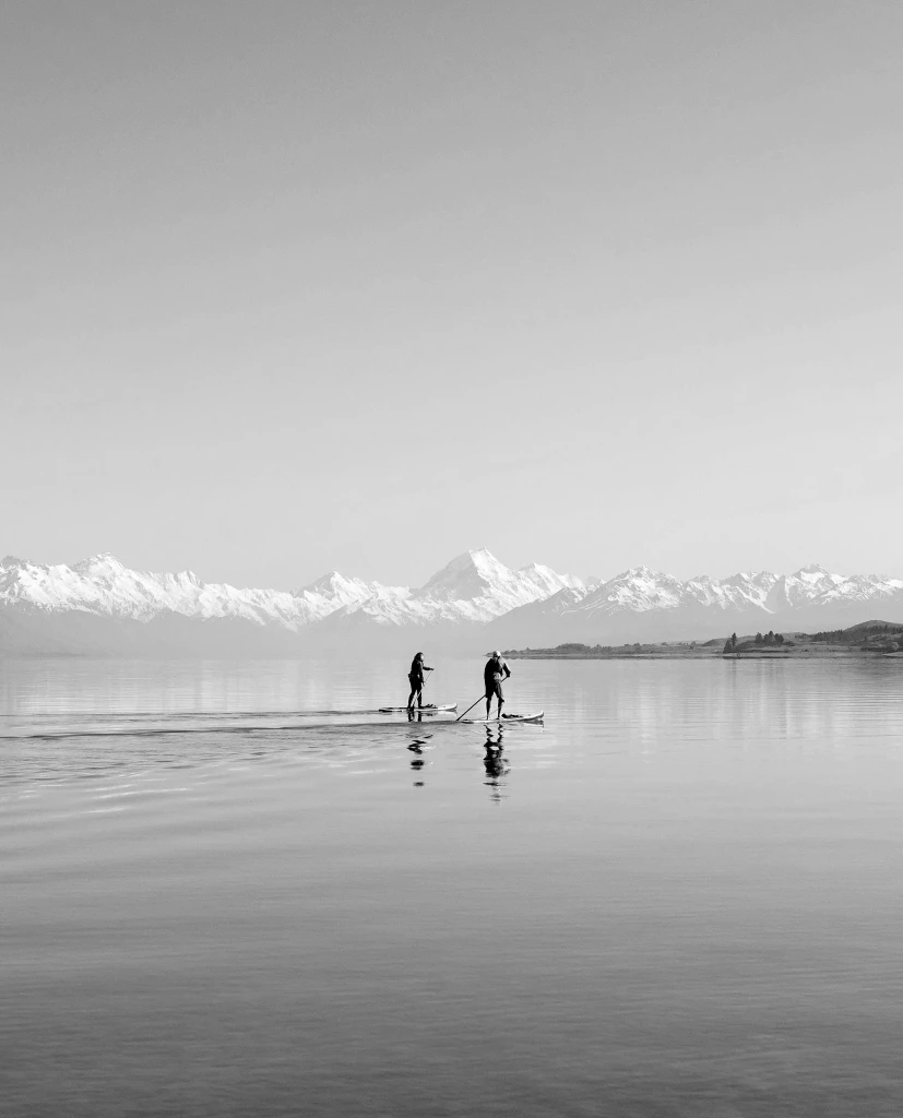 Paddleboarders on Lake Pukaki with Aoraki Mount Cook and the Southern Alps in New Zealand, a private jet charter destination