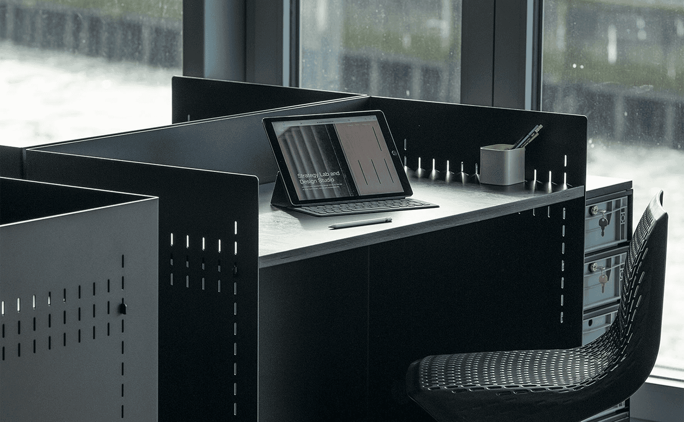 SCOPE Einzelarbeitsplatz mit schwarzen Metallmodulen, Laptop und Rollcontainer.