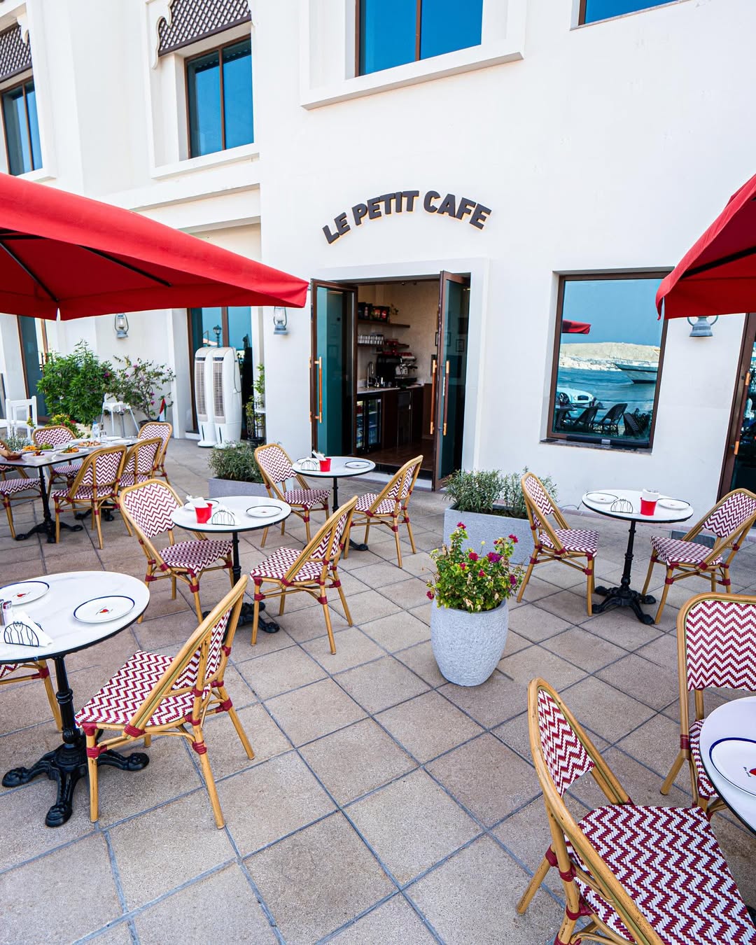 An outdoor seating area at the Le Petit Café overlooking the beach, offering the perfect breezy atmosphere for remote workers or casual meetups.