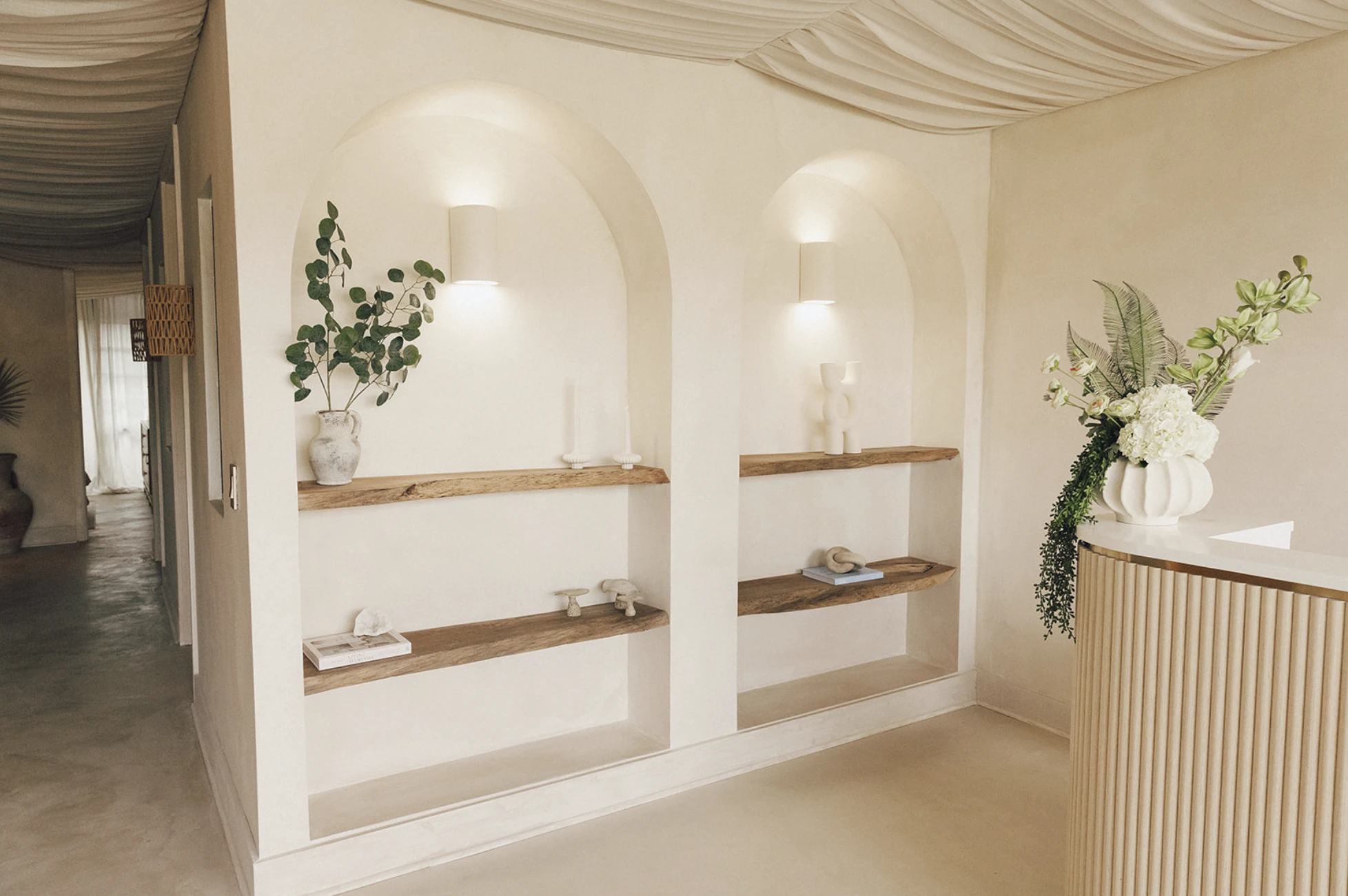 Arched wall niches and natural wood shelving inside Manipura wellness studio reception