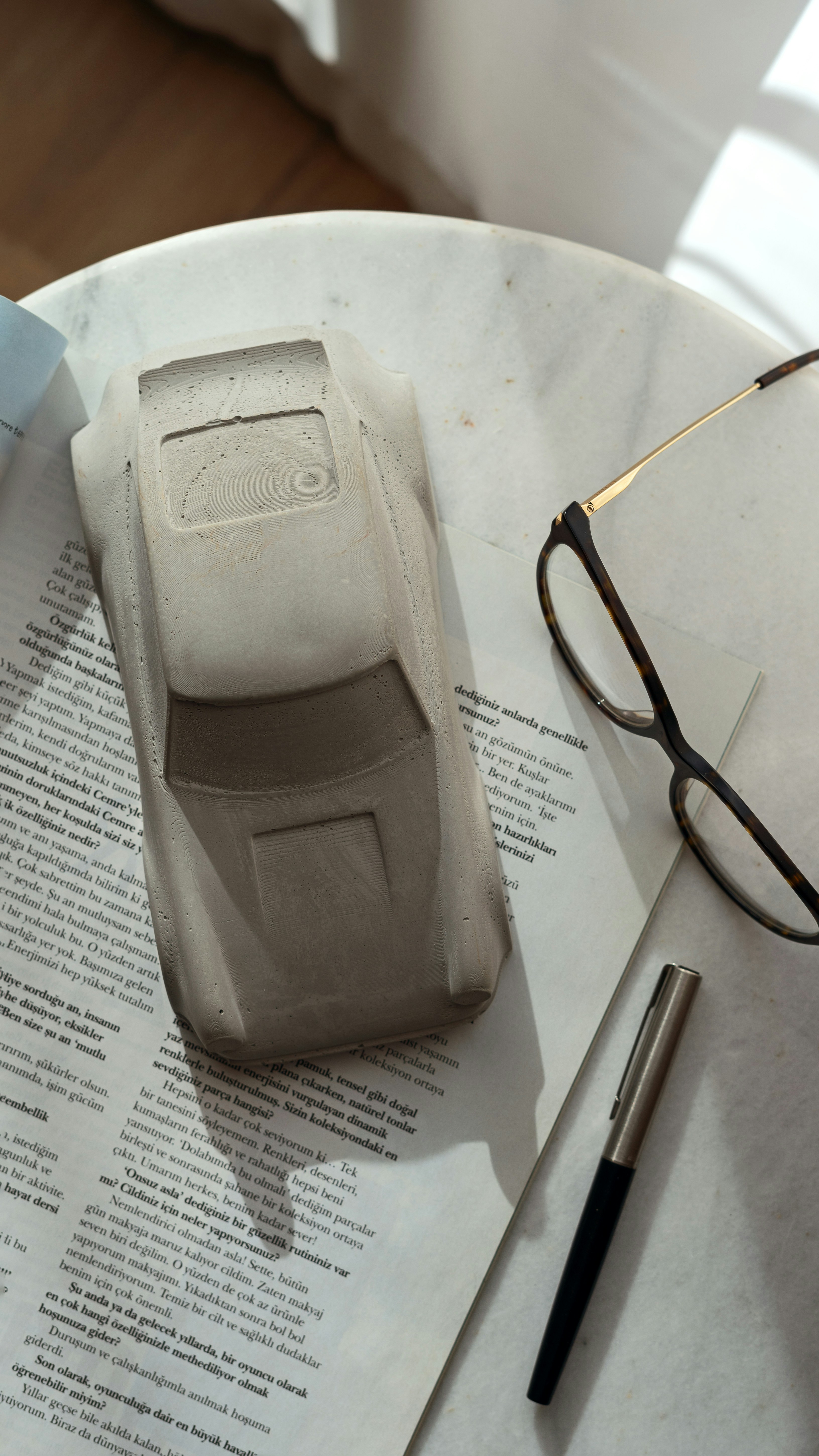 A model car, spectacles, and pen on a newspaper.