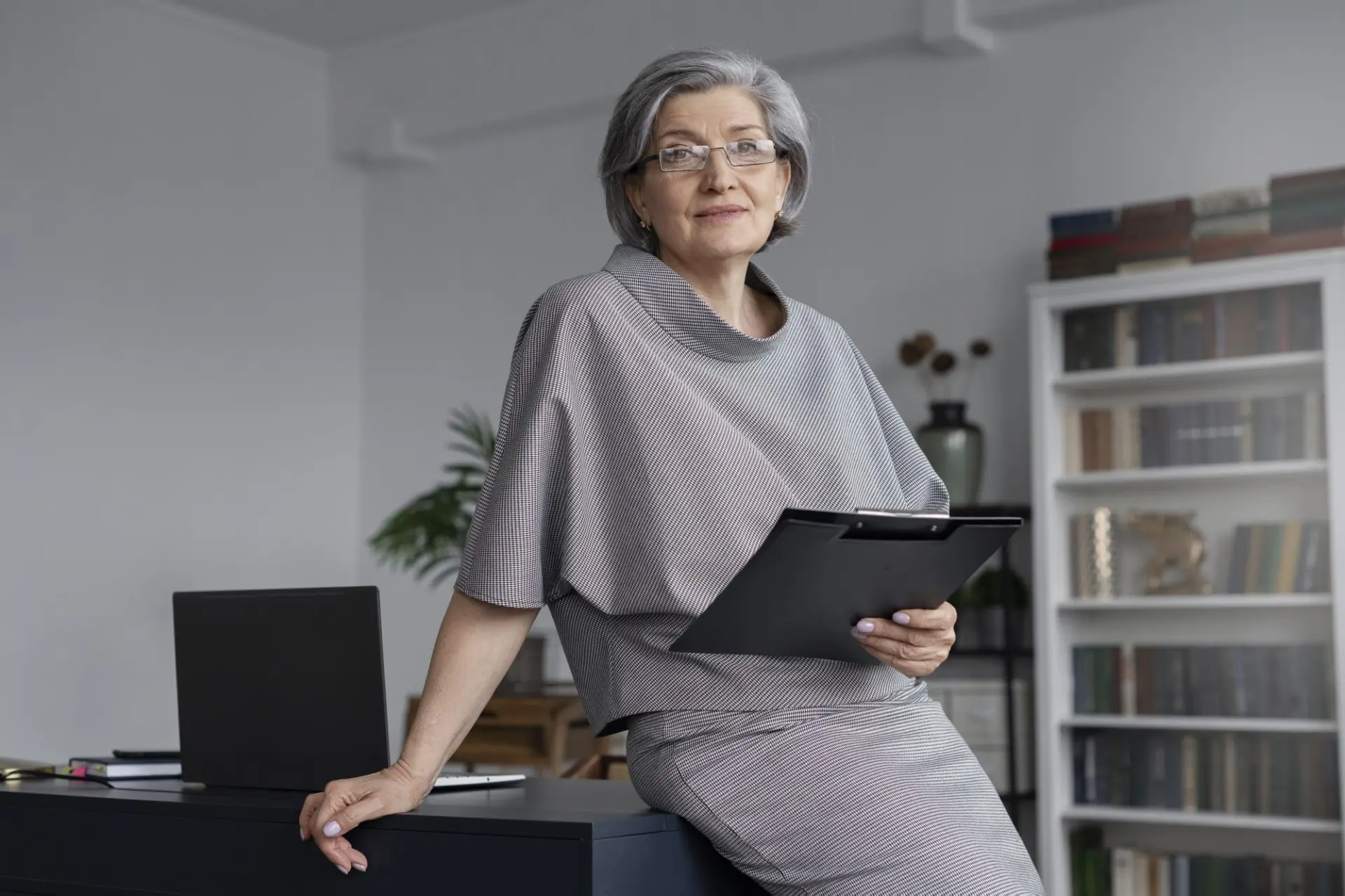 Senior HR consultant holding a clipboard while standing by an office desk