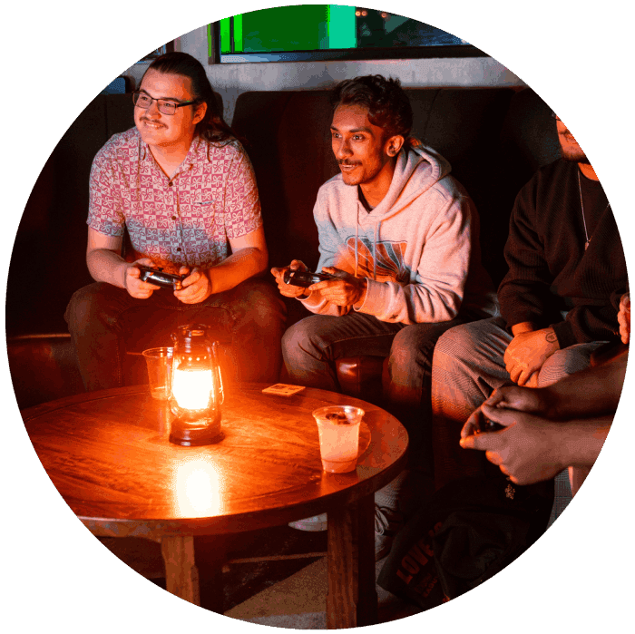 Group of friends sitting in a booth in the Fortress Tavern playing console games