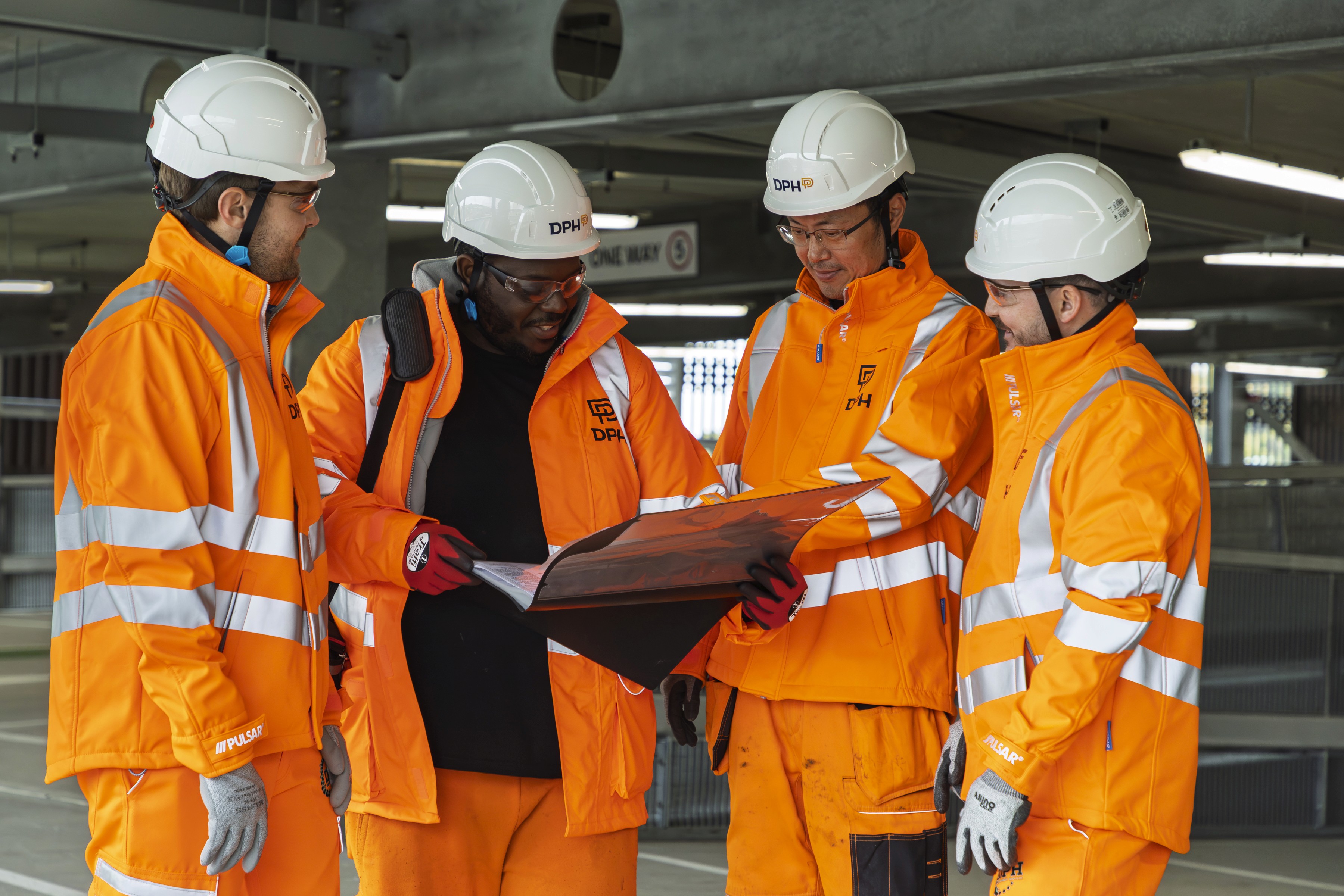 Modern glass building with illuminated interior and reflections at sunset