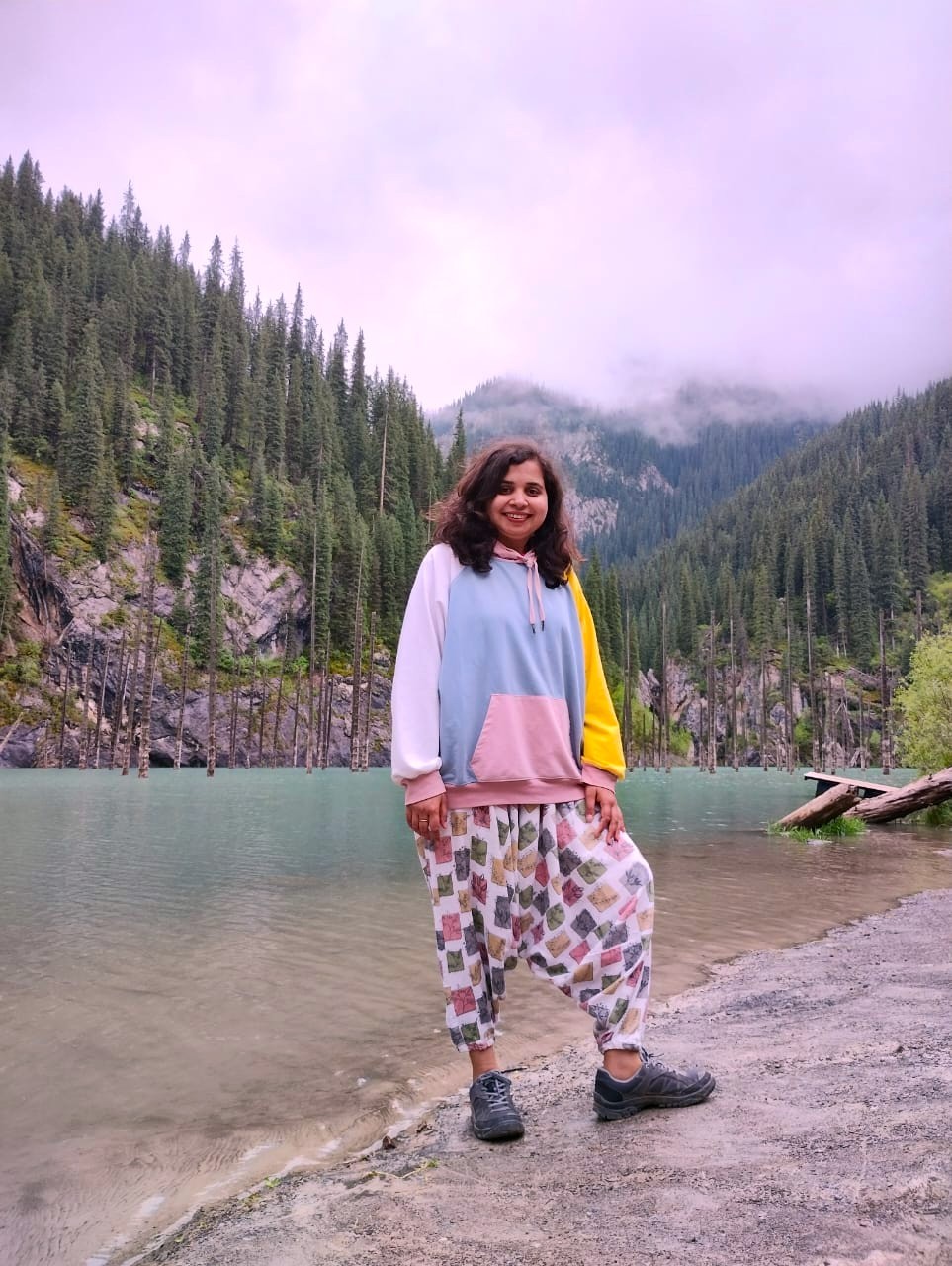 man standing near cliff looking at body of water during daytime