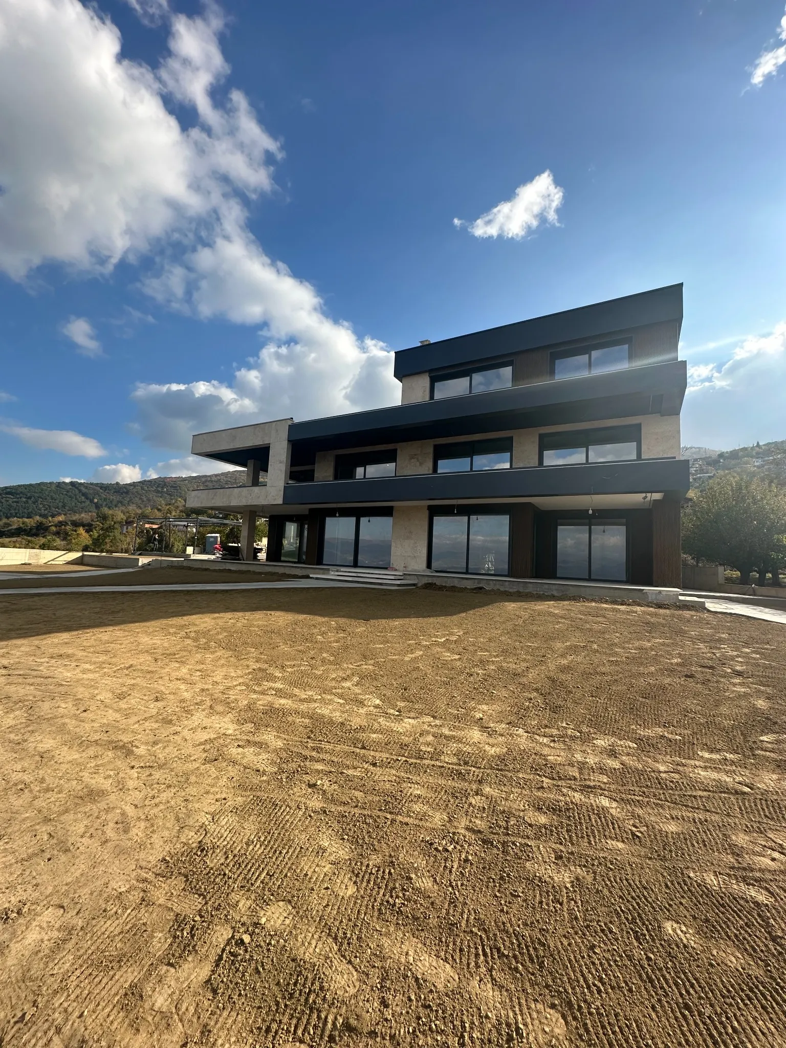 Wide-angle view of Villa Nerezi in Nerez, Skopje, emphasizing its clean horizontal lines, expansive terraces, and surrounding terrain. Terraplan Partners handled architectural planning and supervision.