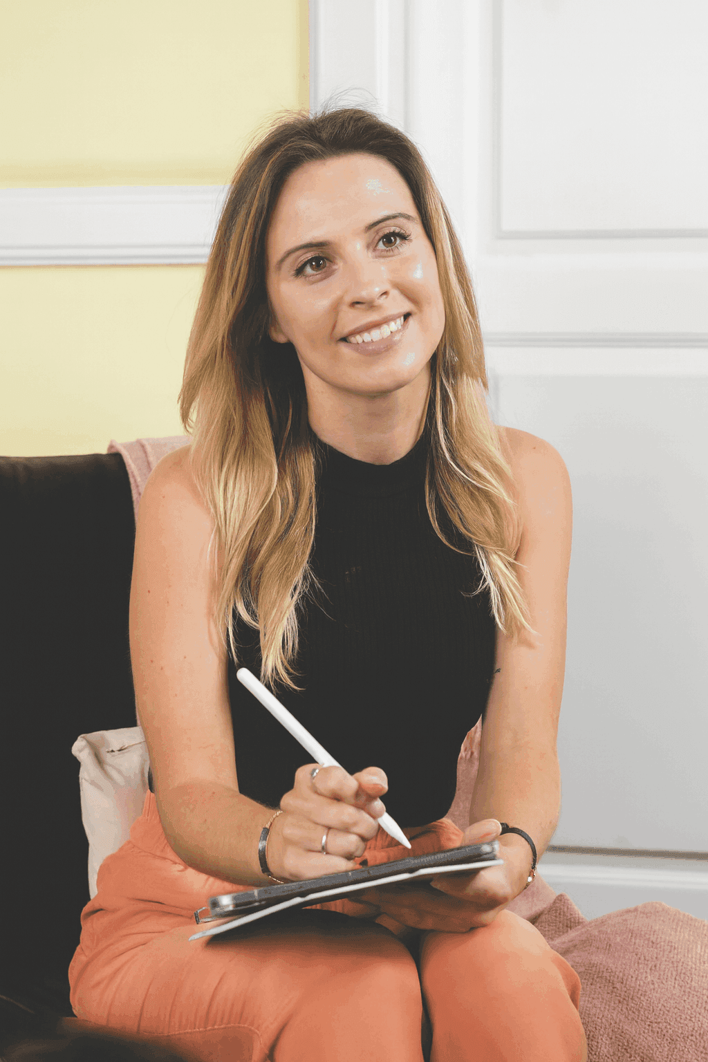 Chloe seated with a tablet and stylus, smiling in a bright therapy setting.