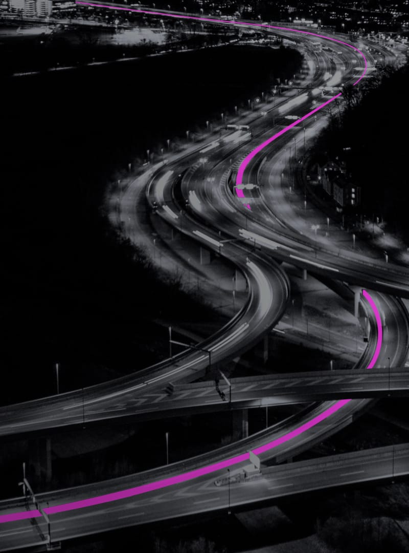 A busy highway at night with a route marked in pink