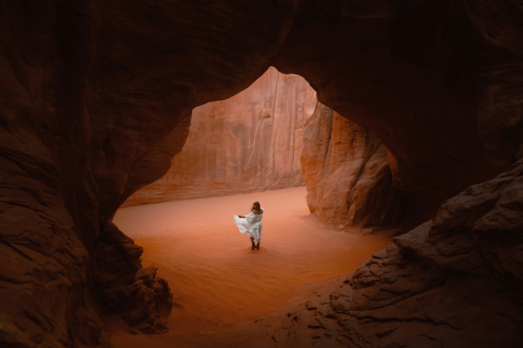 A person stands in a sandstone cave.