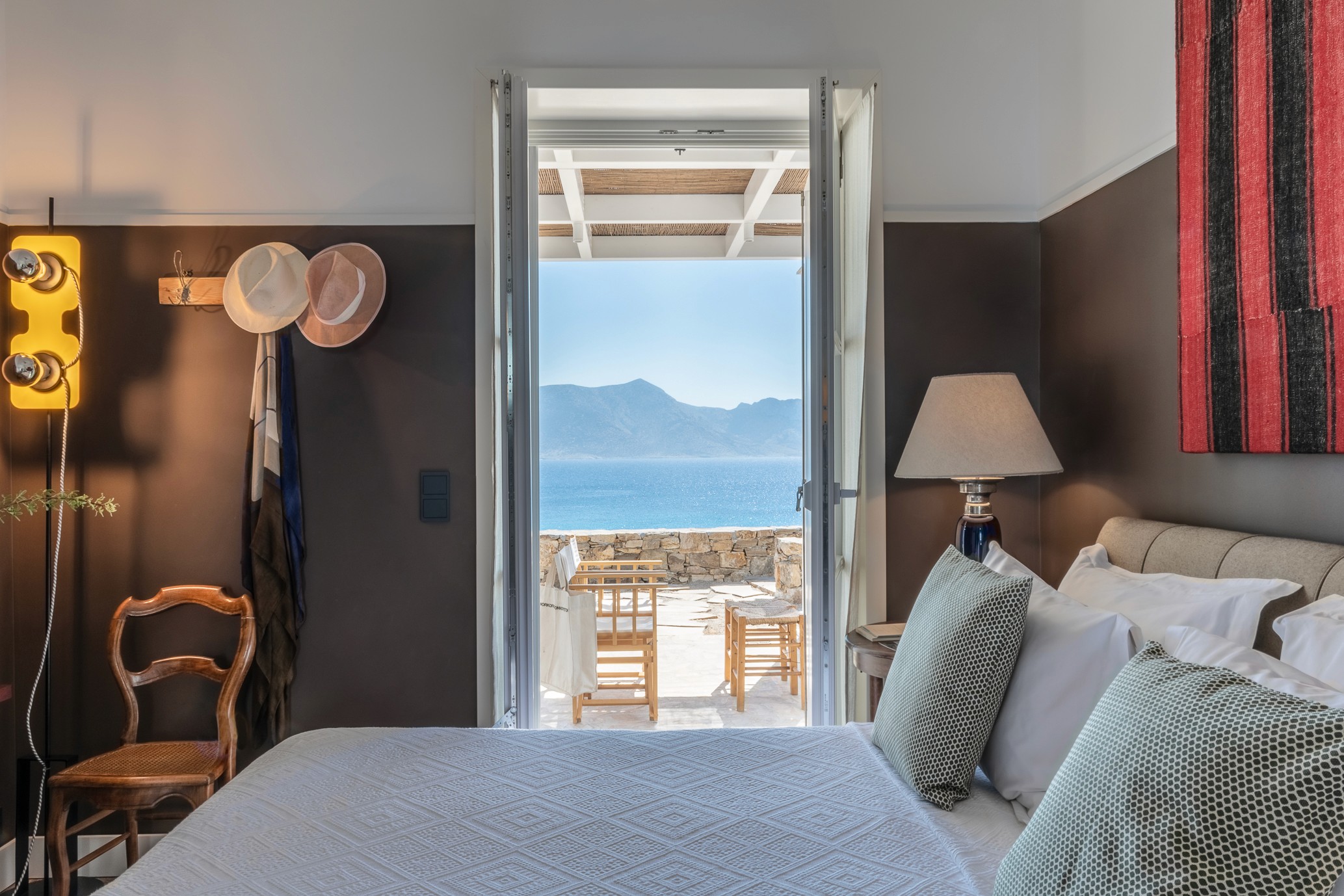 Bedroom with open windows looking out onto a terrace and the sea