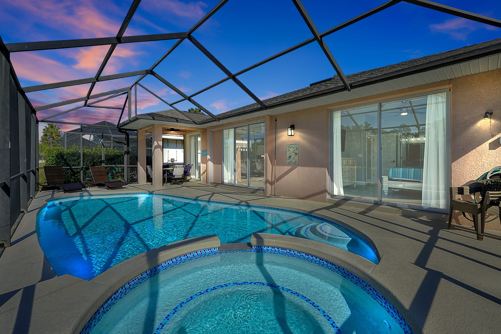 Screened pool and spa with lounge chairs and patio dining.