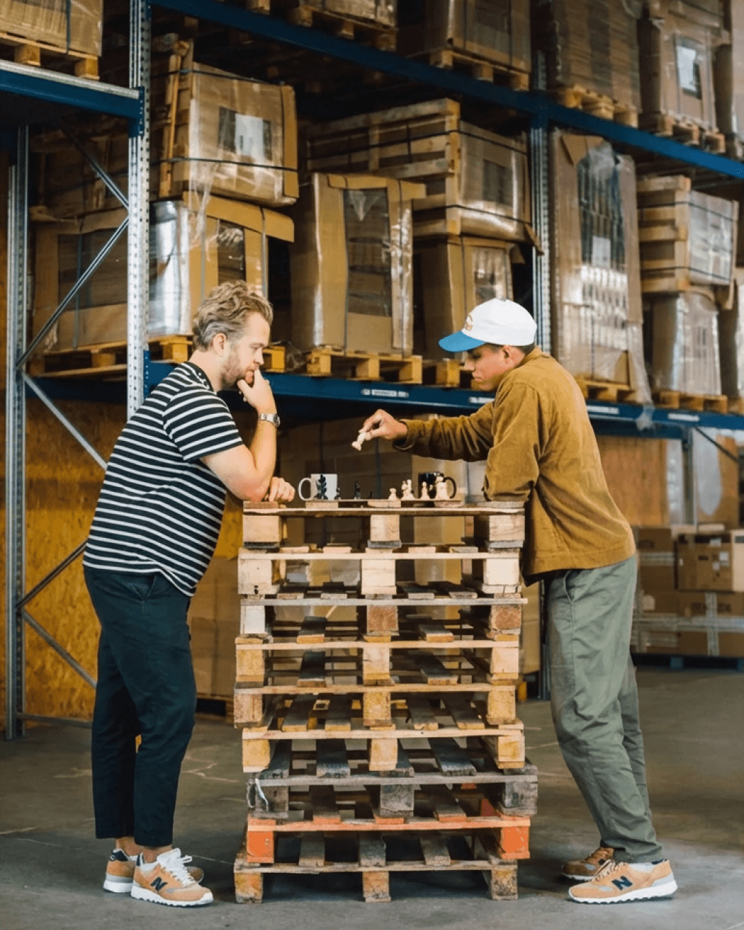 A person sewing a light beige leather handbag using a sewing machine, with soft natural light casting shadows across the workspace.