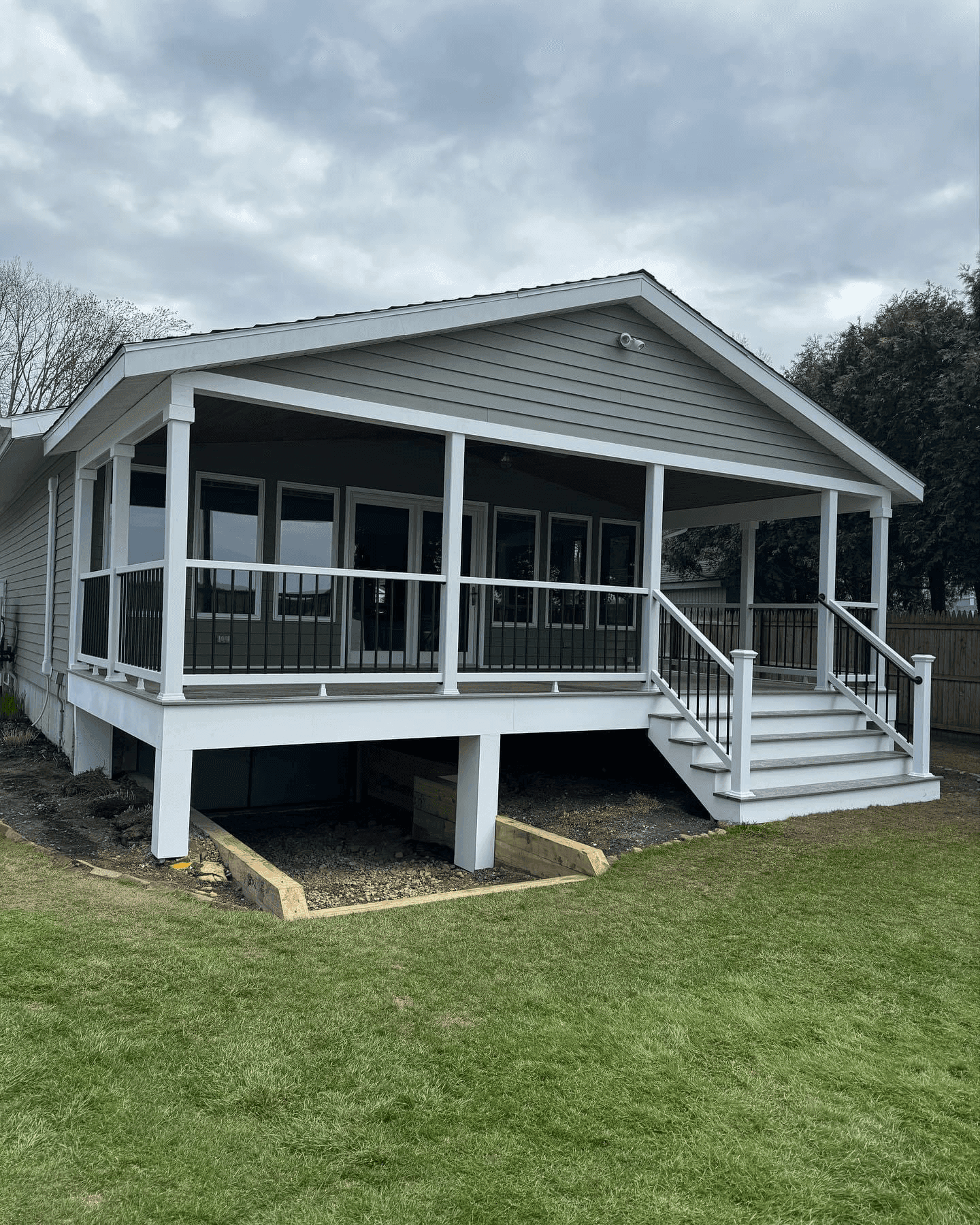 Grey Trex deck with white railings looking out at a lake with a dock