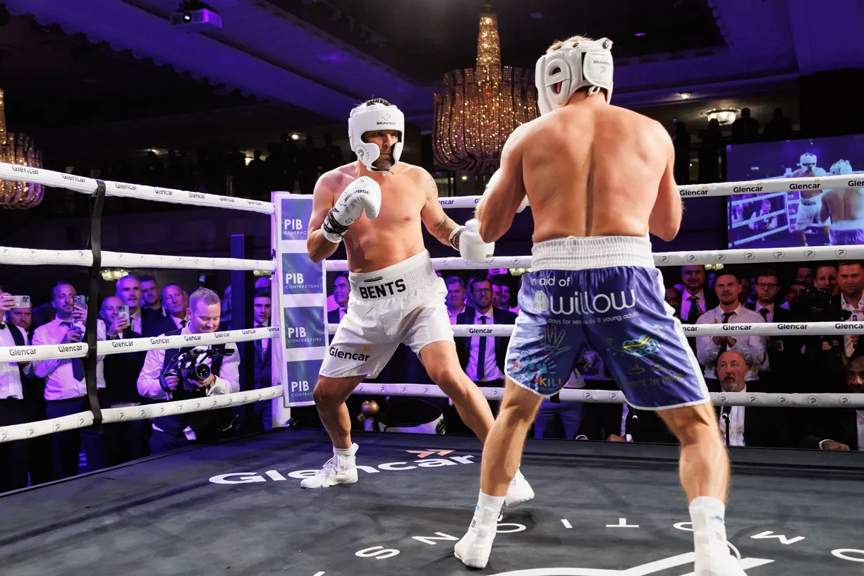 Two boxers in a ring with a crowd watching.