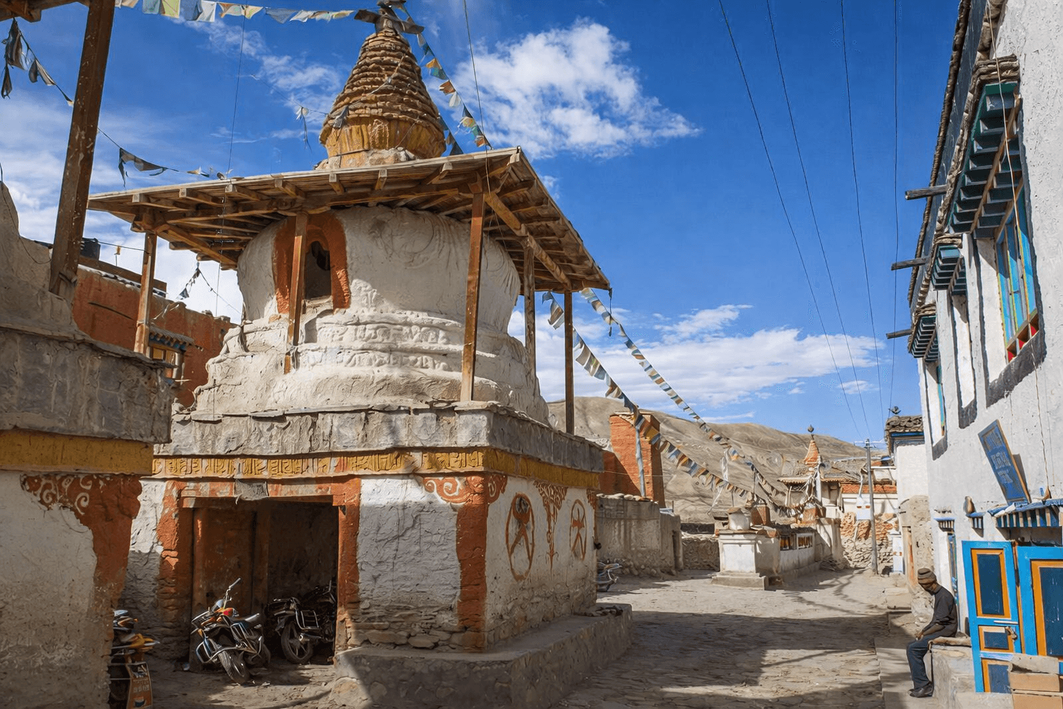 people walking on beach near brown concrete building under white clouds and blue sky during daytime