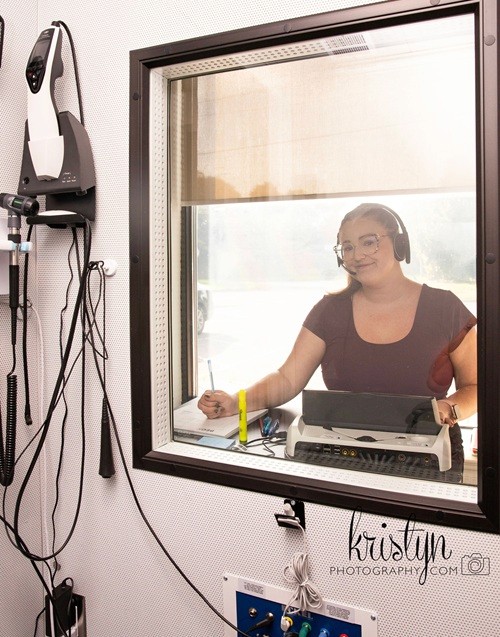 An audiologist testing the hearing of a patient in a sound booth