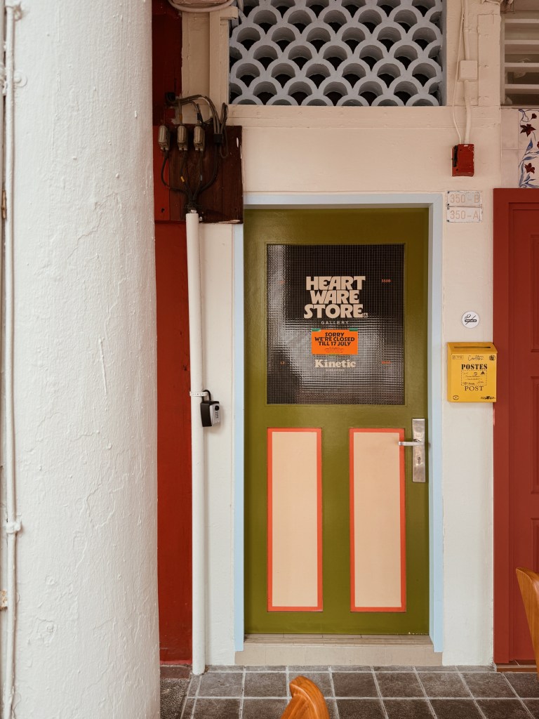 A colorful shopfront featuring a green door with 'HEART WARE STORE' signage, surrounded by vibrant wall colors and decorative architectural details.