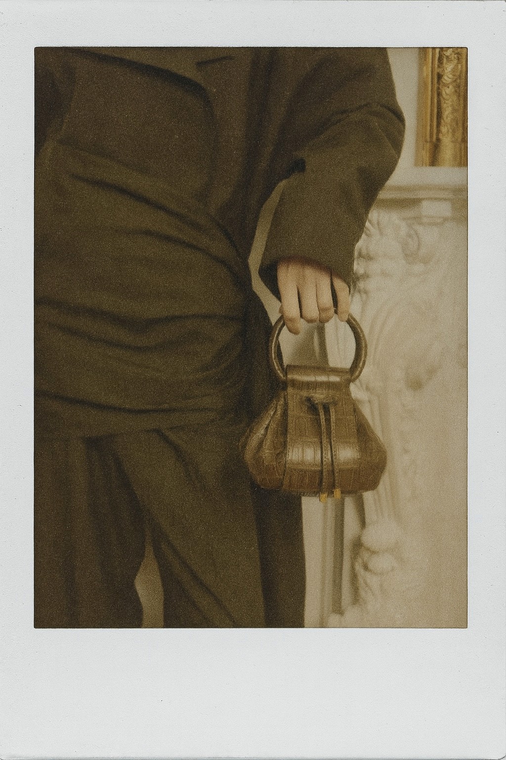 Sculptural display of curled, tan leather-like material rolls arranged on a wooden block with dried wheat stems, set against a beige background.