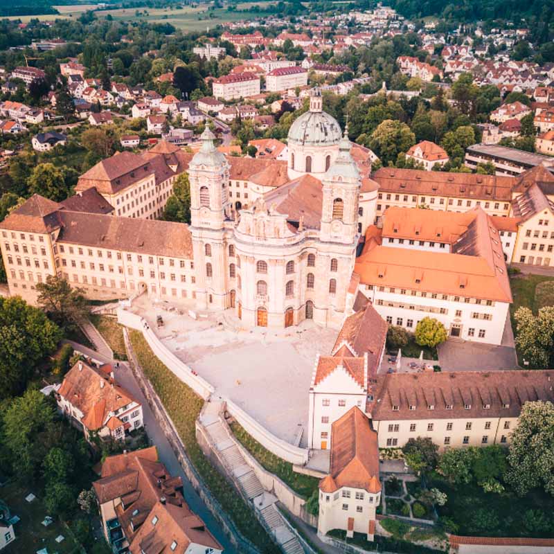 New York City skyline at twilight featuring the Empire State Building and other skyscrapers illuminated against a purple-blue sky.