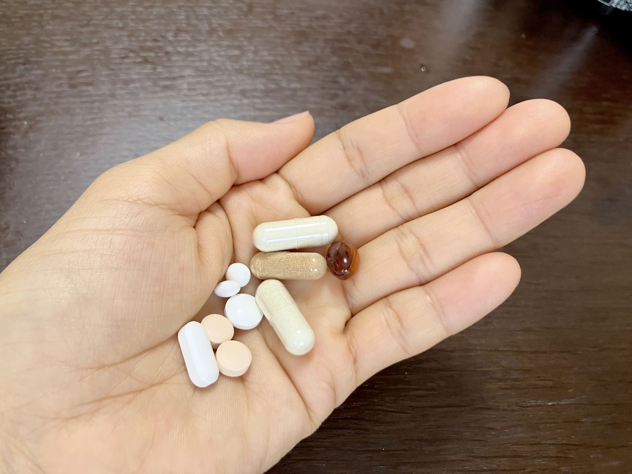 手のひらに乗せた複数のサプリメント。薬機法・景品表示法により効能効果の表現が制限されるヘルスケア・食品領域の特殊性を表す