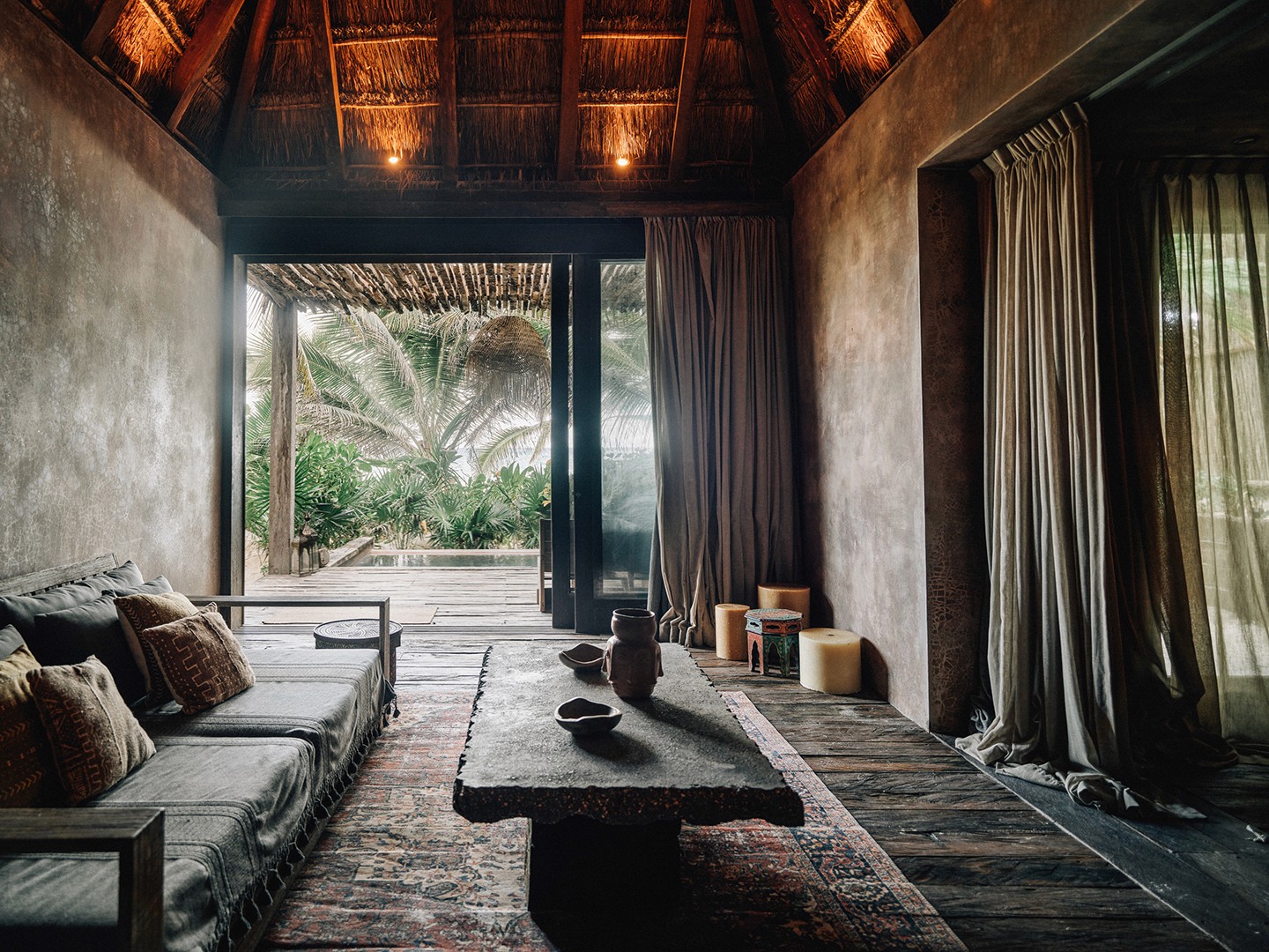Premier Suite at Nômade Tulum highlighting part of the bed with pillow and cushion, and bright and beautiful lamp next to the bed.