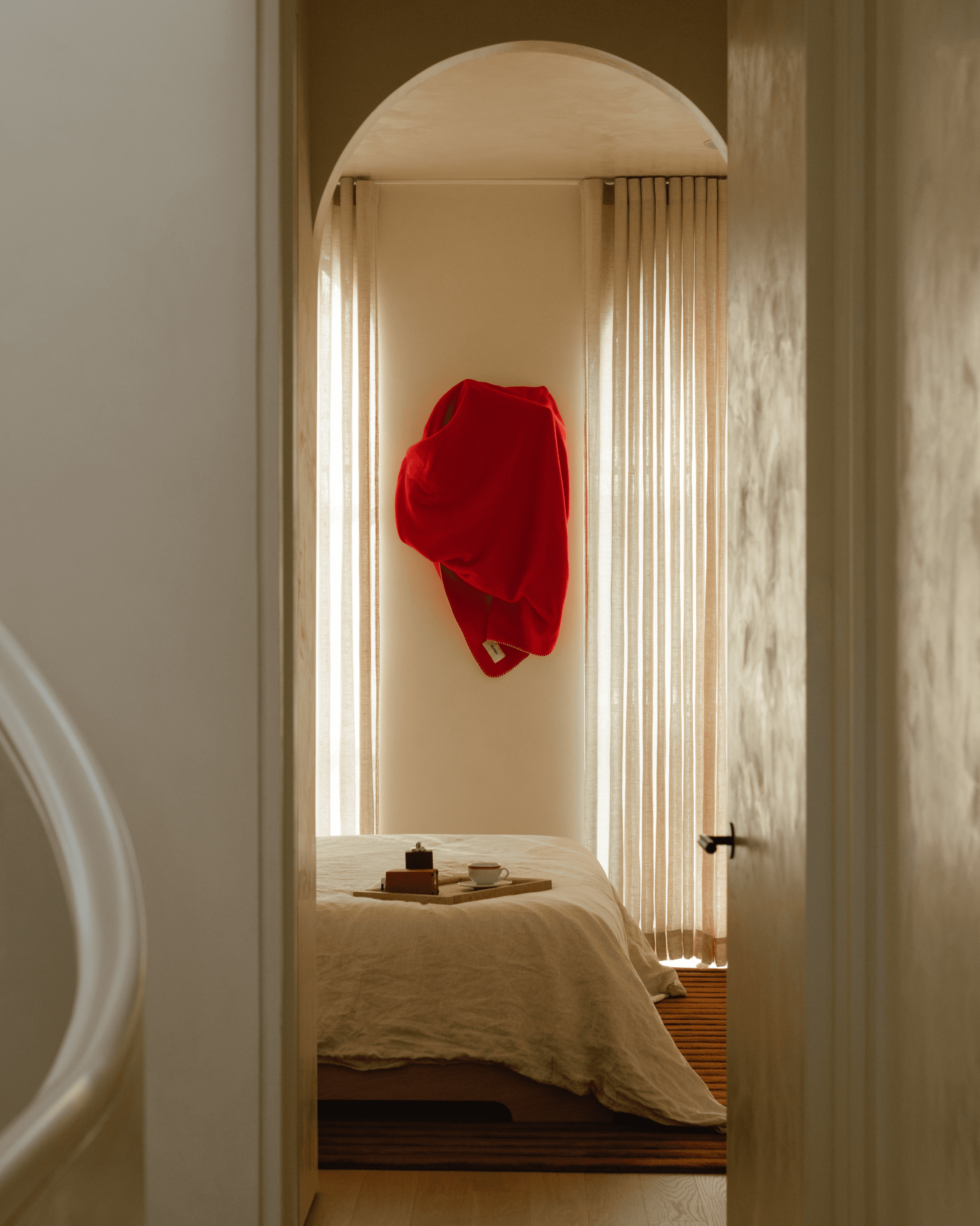 A cozy scene showing a person dressed in white lounging on a sofa, surrounded by plush blankets in cream and deep teal. Both blankets feature the "NORMY" label, highlighting the brand, and add a touch of comfort and style to the setting, which also features colorful tile flooring.