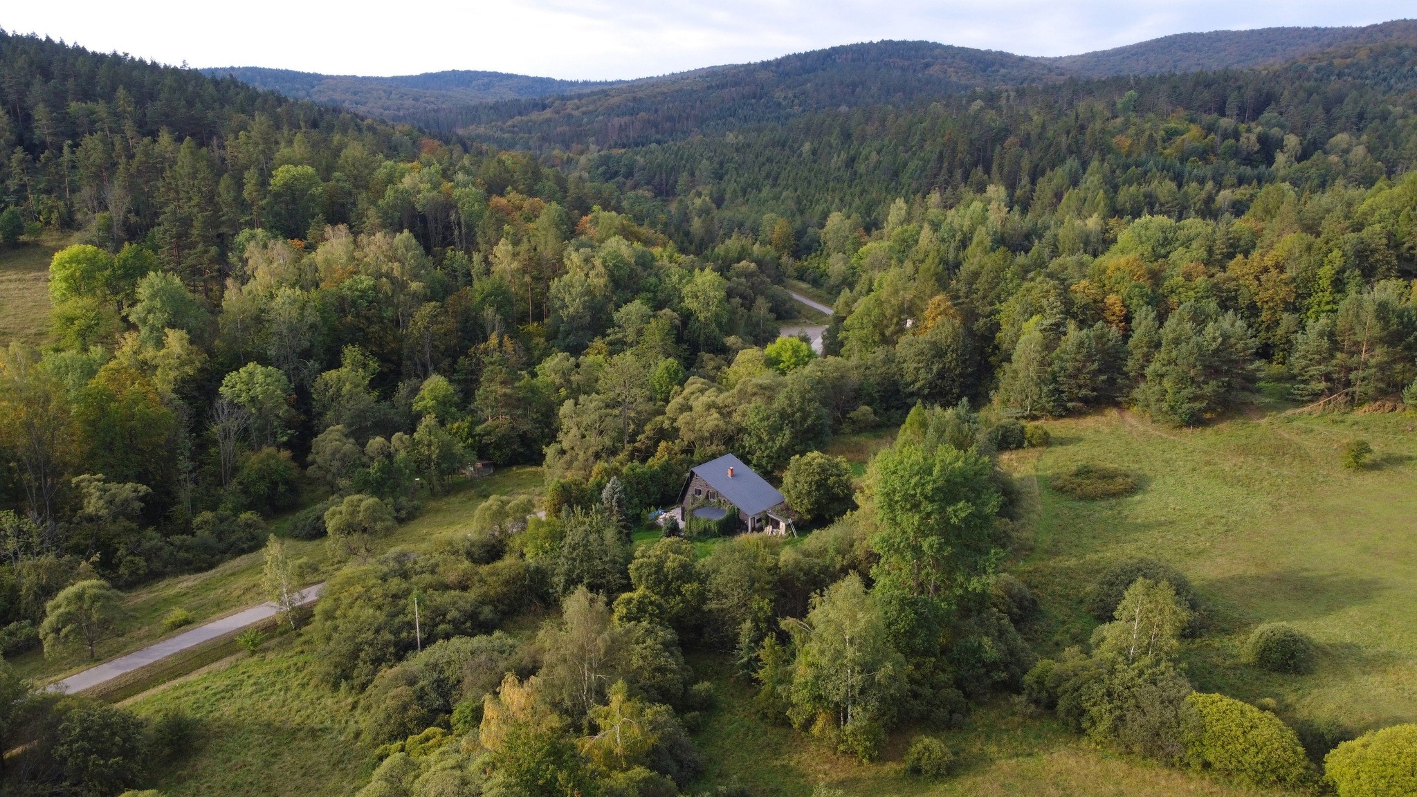 widok  z lotu ptaka na góry Beskidy i dom położony w środku lasu